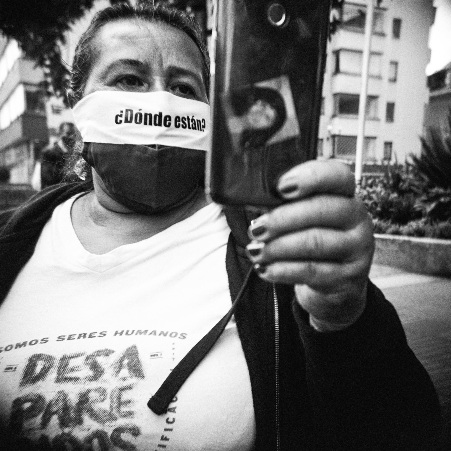 Inés Castiblanco, sister of Ana Rosa Castiblanco, records a video during a protest in front of the Special Jurisdiction for Peace (JEP) building in Bogotá, Colombia. &nbsp;She wears a mask bearing the question: &lsquo;Where are they?&rsquo; &nbsp;Ana Rosa, a kitchen assistant at the Palace of Justice, disappeared during the 1985 siege of the Palace, when she was 32 and pregnant. Her remains were returned to her family in 2017. The JEP was established in 2017 to investigate and try abuses committed during Colombia&rsquo;s internal conflict.