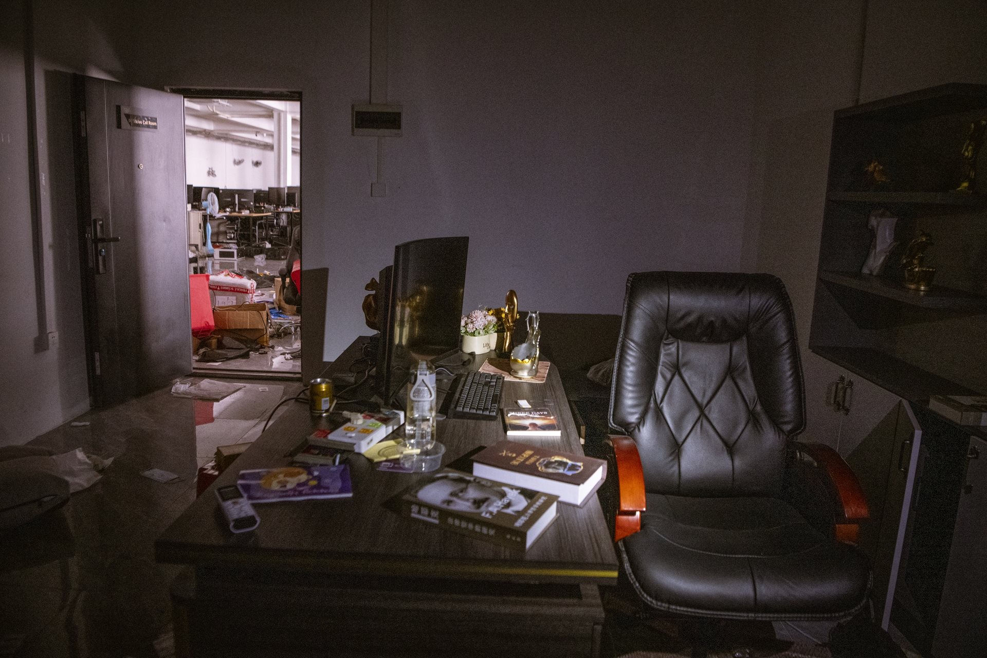 Fake books and other props furnish an abandoned streaming room decorated to appear on camera as an executive office. These sets were used for webcam streaming to convince targets they were speaking with successful crypto-investors or legitimate business professionals. Min Let Pan, Myanmar.