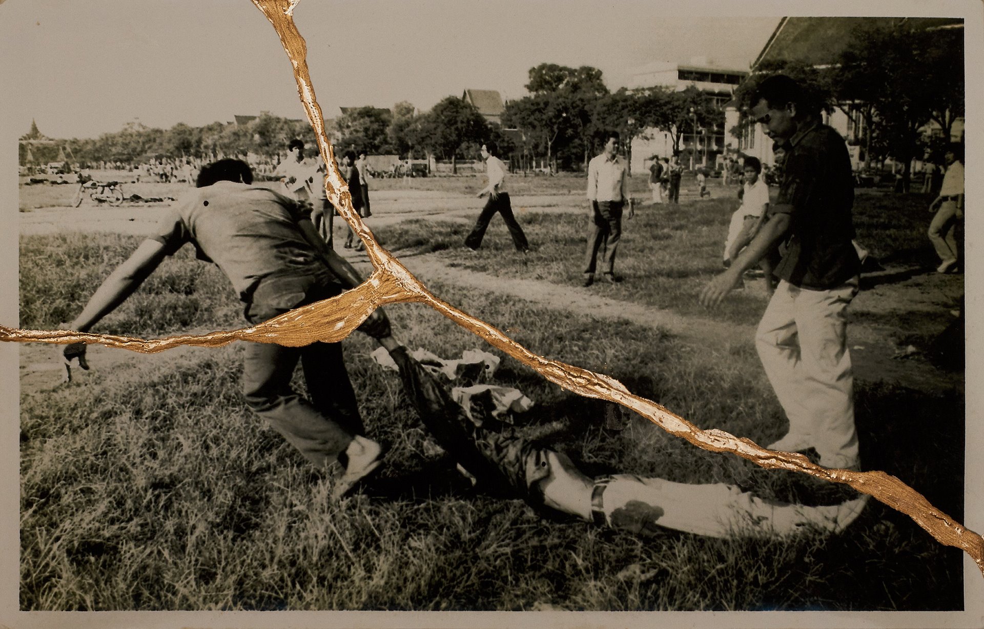 <p>Royalist civilians pull a lifeless body through the grass in Sanam Luang, Bangkok, Thailand. Together with the military, members of royalist civilian groups lynched students, hanged them from trees and burned their bodies.</p>
