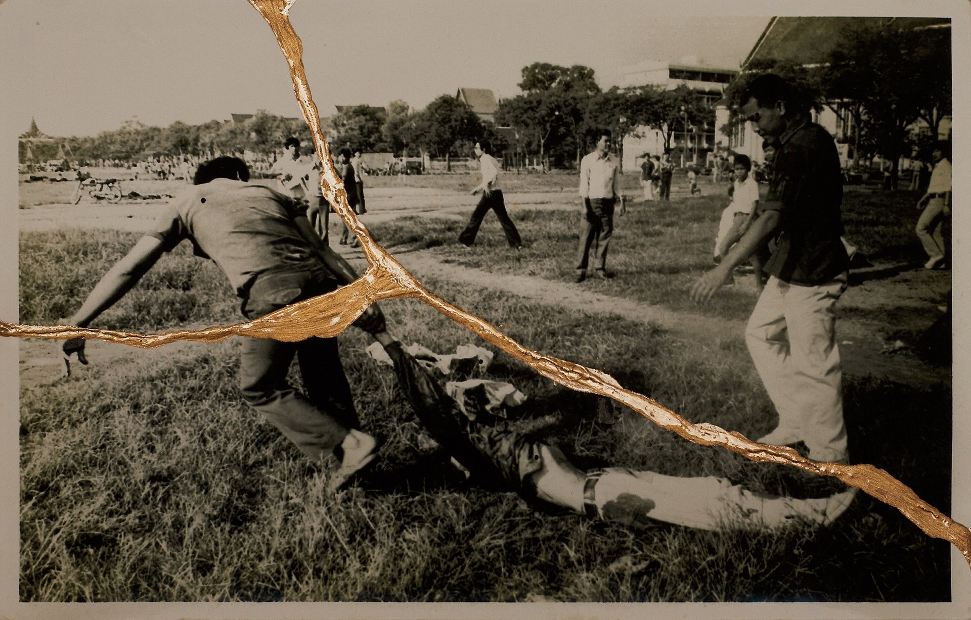 <p>Royalist civilians pull a lifeless body through the grass in Sanam Luang, Bangkok, Thailand. Together with the military, members of royalist civilian groups lynched students, hanged them from trees and burned their bodies.</p>
