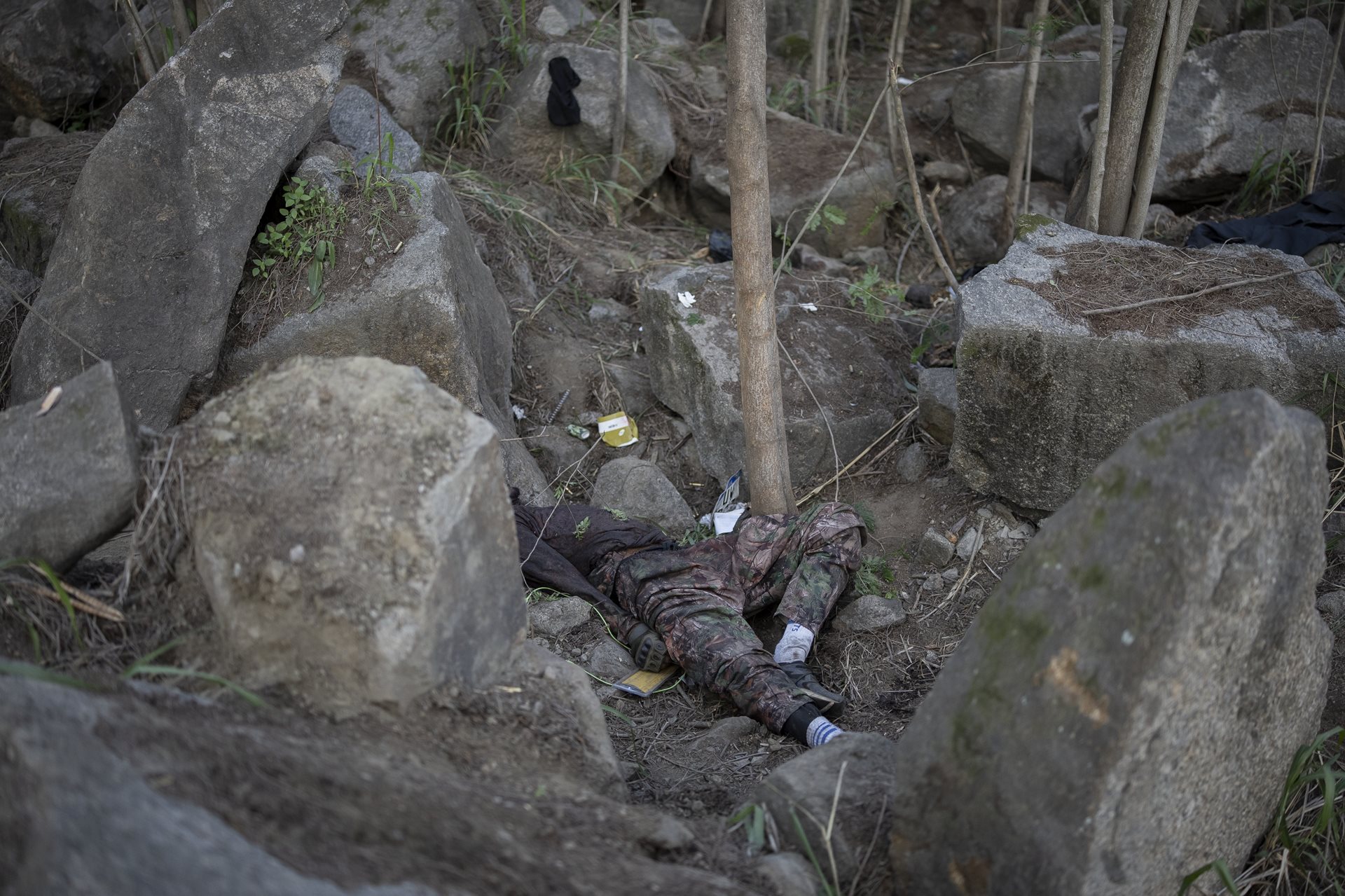 A body lies in the Vacaria forest between the Penha and Alemão favelas, in Rio de Janeiro, Brazil. Police ambushed fleeing individuals here, leaving victims overnight.