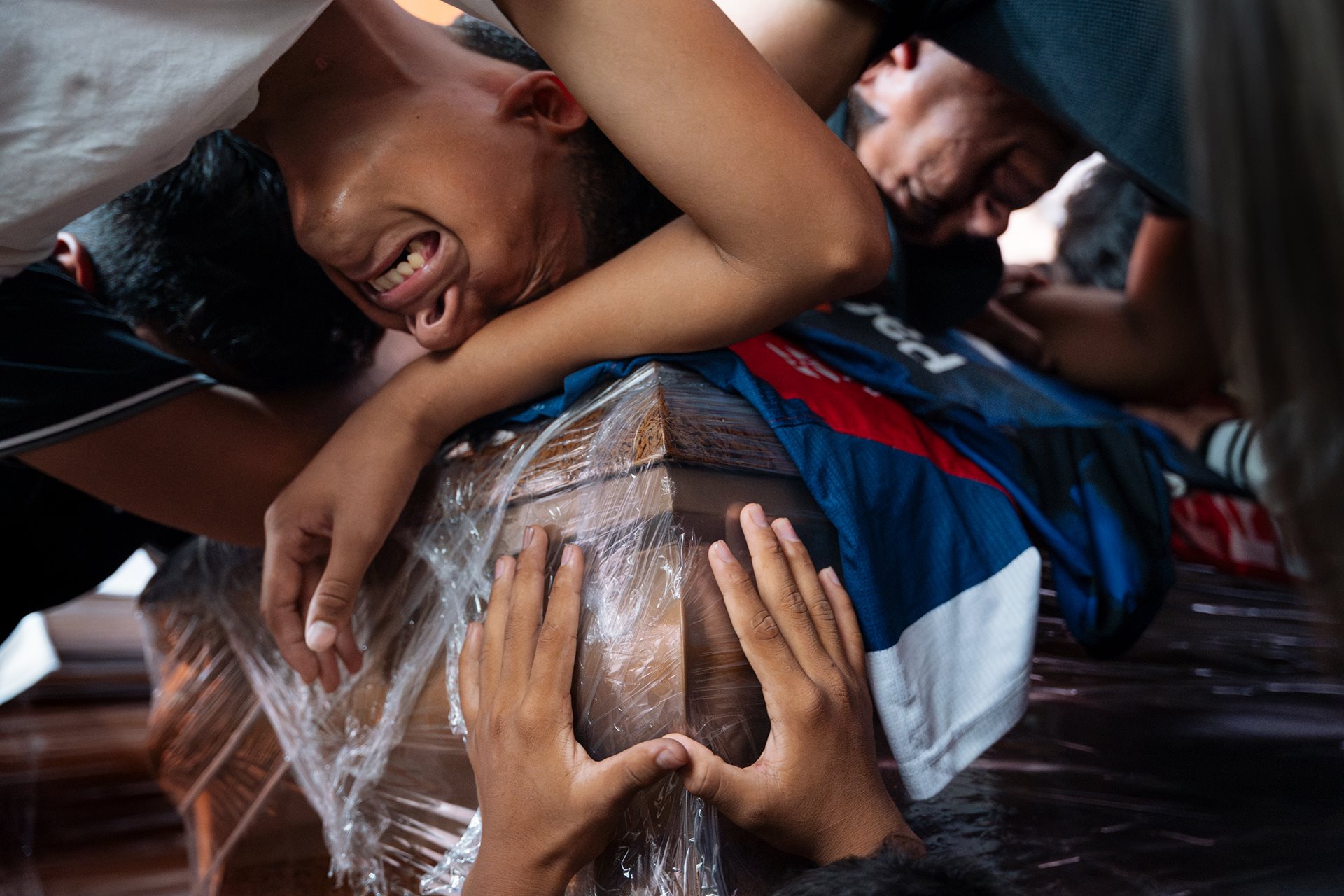 Teammates and a coach mourn over the plastic-wrapped coffin of 15-year-old Ismael Arroyo in the Las Malvinas neighborhood in Guayaquil, Ecuador. Ismael and three other boys were detained by military personnel on 8 December 2024; their burned remains were found two weeks later near an air base. The case has sparked nationwide outrage over racial profiling and military abuses.