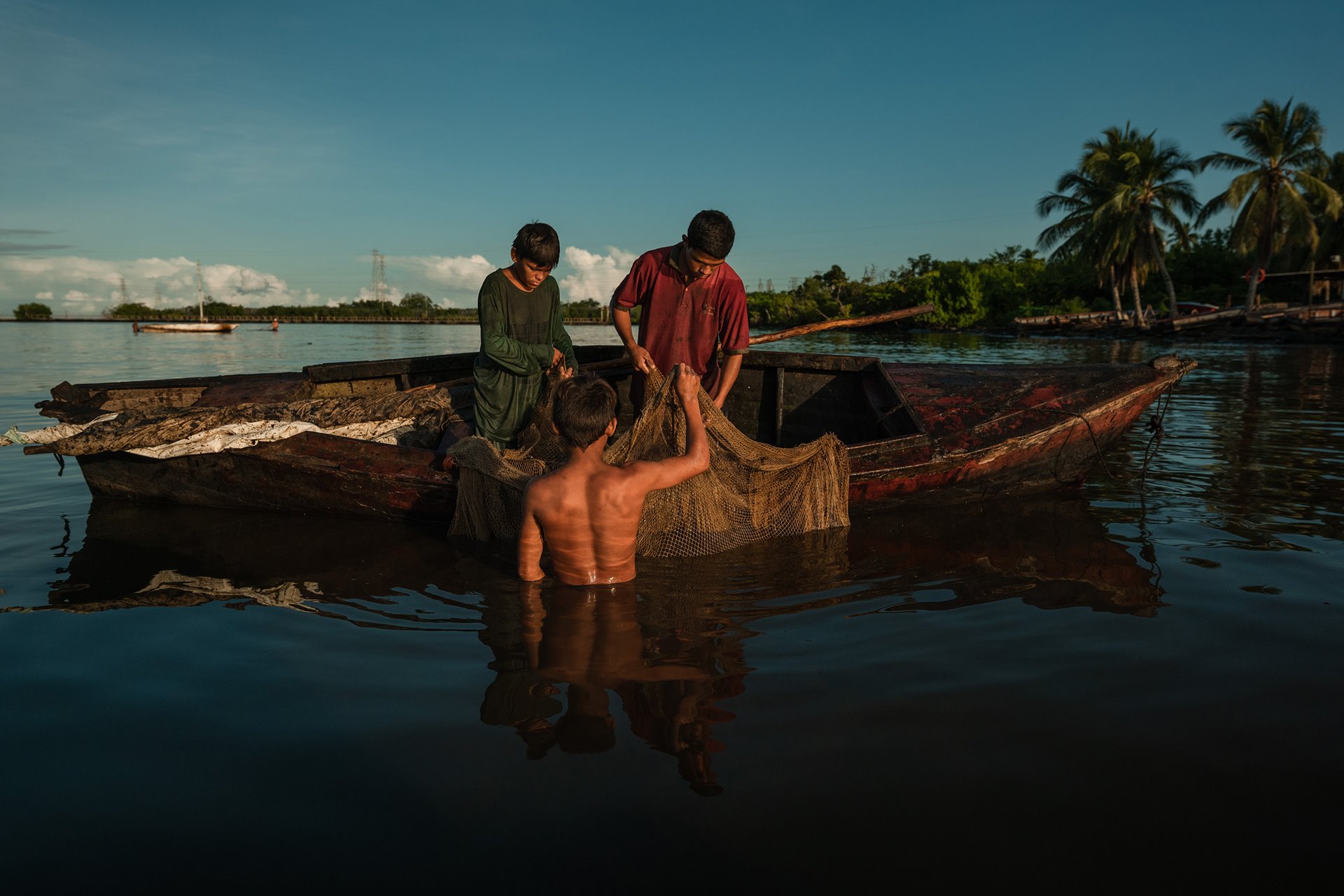 Diego Méndez (14), Manuel Méndez (13), and Miguel Méndez (16) fish in Lake Maracaibo, Cabimas, Venezuela. Crude oil from damaged pipelines spilled into the lake smears fishing boats, clogs outboard motors and damages nets.&nbsp;