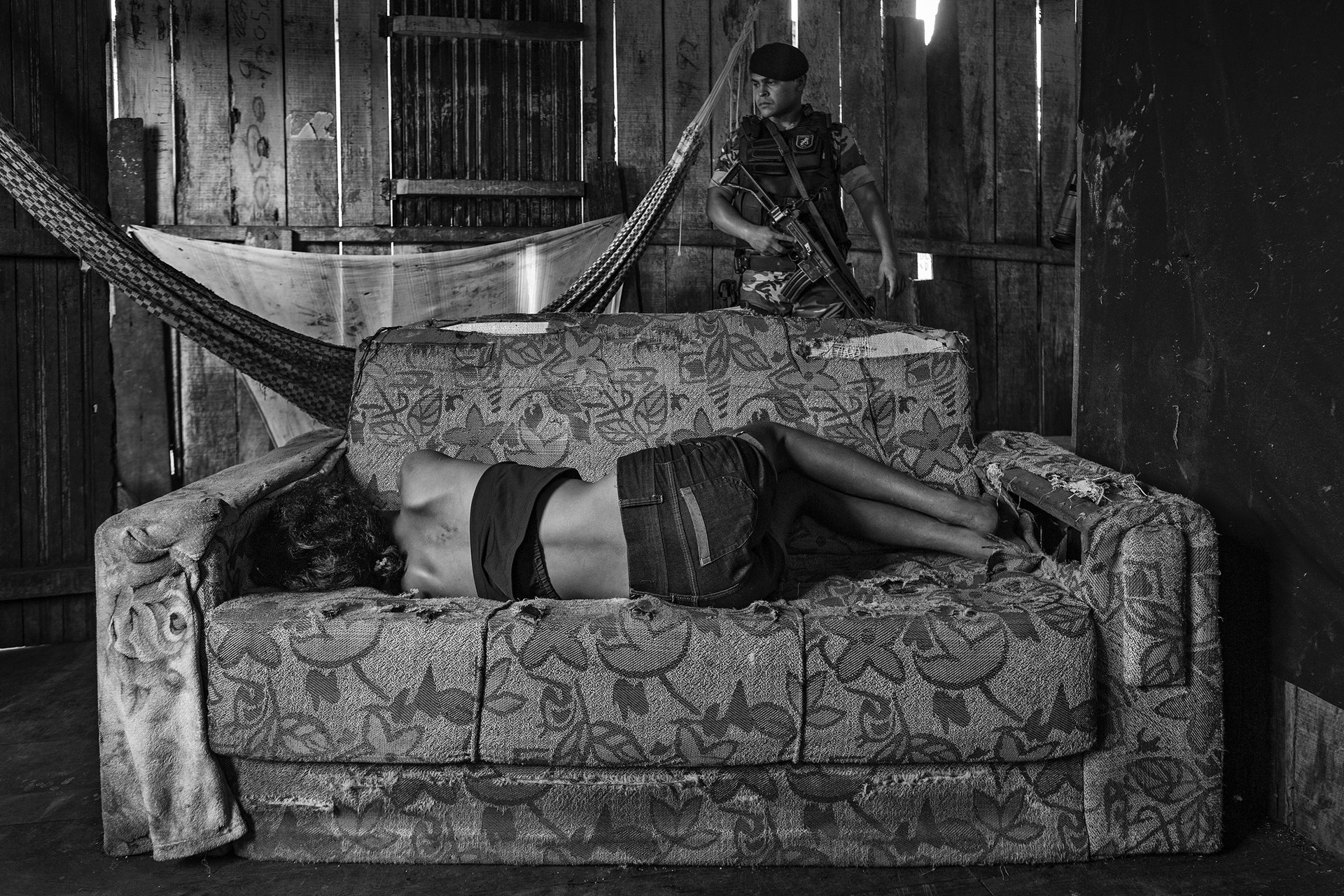 A woman lies on a sofa as a police officer searches for drugs in a shack frequented by crack cocaine users, on Olarias Street in one of the most violent neighborhoods in Altamira, in Pará, in the Brazilian Amazon.