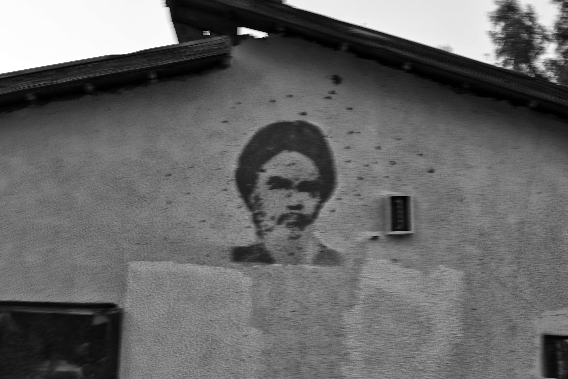 A painting of the Ayatollah Khomeini, spattered with marks made by stones, adorns a house in a border village in northern Iran.