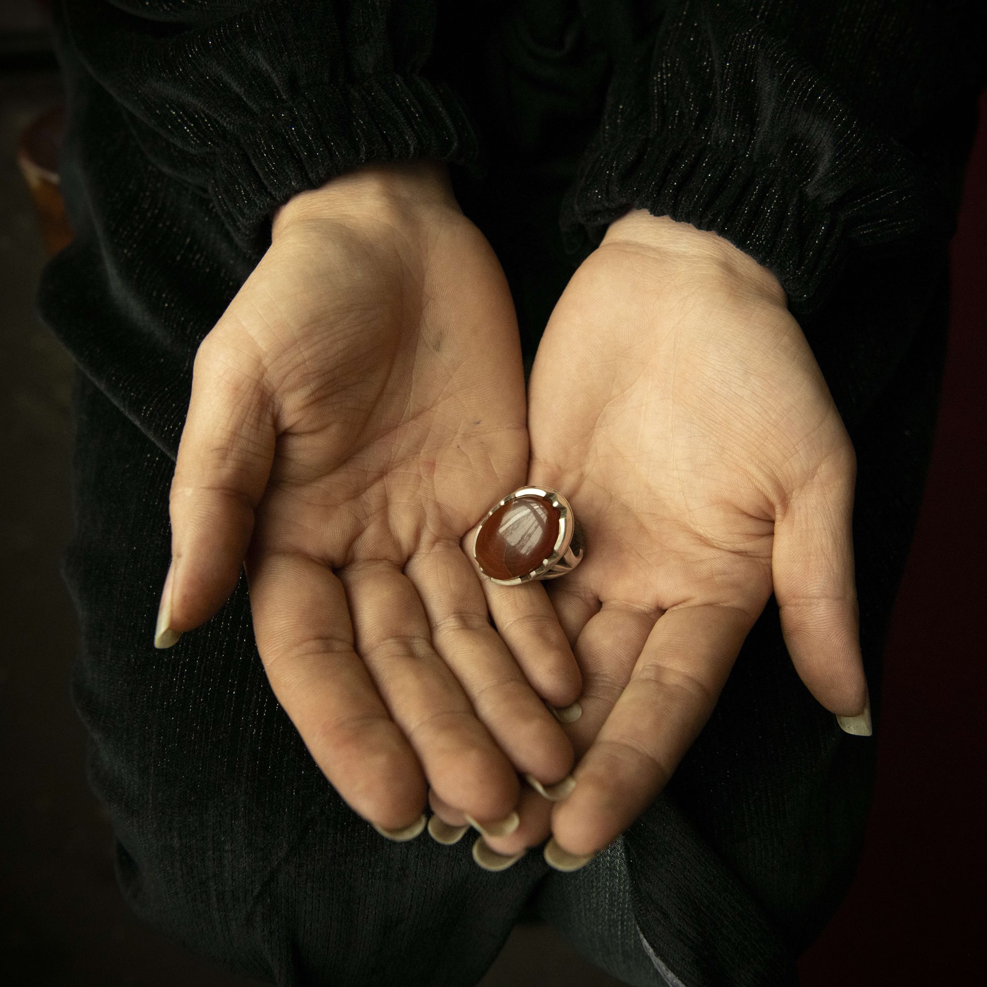 Halima (28), a widowed mother of three, holds a ring that belonged to her late husband, in Kabul, Afghanistan. When police arrested a friend for not wearing a hijab correctly, they also detained and beat Halima after finding evidence of activism on her phone. Her husband had a fatal heart attack on hearing the news. Defiant, Halima continues her activism.