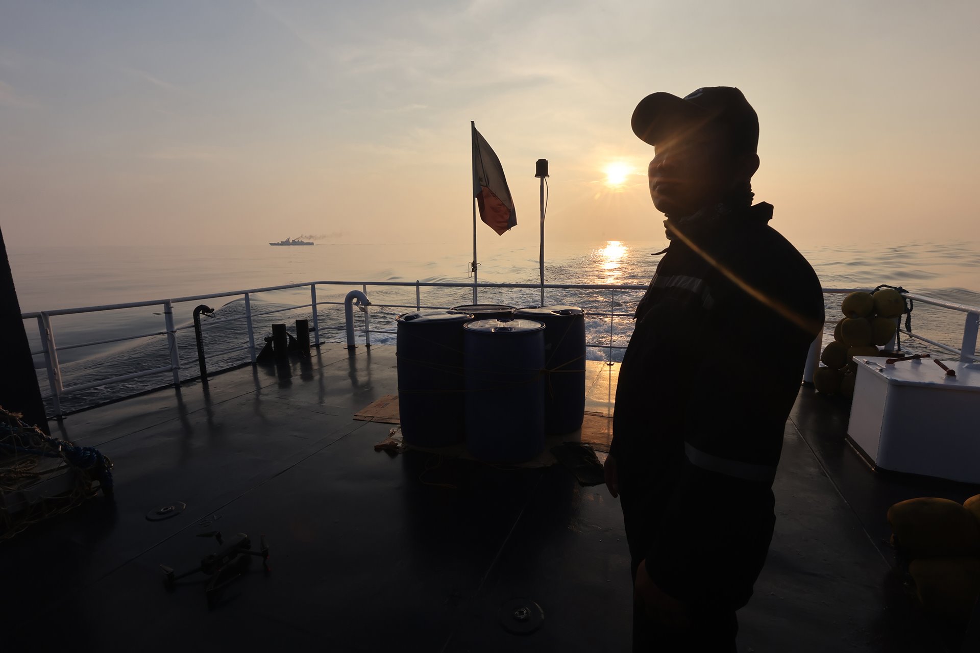 A member of the Bureau of Fisheries and Aquatic Resources stands beside barrels of oil set to be delivered to Filipino fishermen working near Scarborough Shoal, off Zambales province, Philippines.