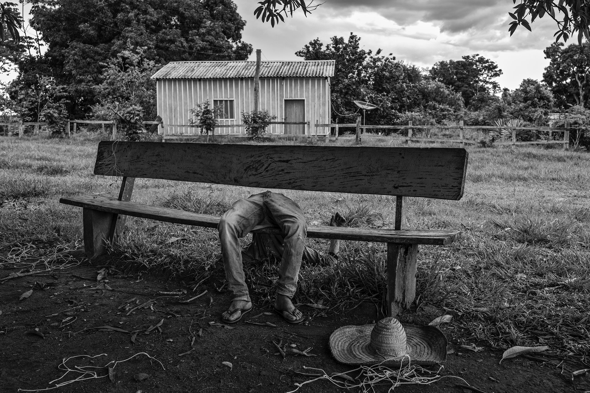 <p>A member of the Quilombola community &ndash;&ensp;an Afro-Brazilian community consisting of Black Brazilians, some of whom are descendants of enslaved peoples from the African continent &ndash; lies passed out drunk on a bench, in Pedras Negras, São Francisco do Guaporé, Rondônia, Brazil. The process of providing land deeds to communities started by former enslaved people was already slow before Jair Bolsonaro&#39;s election. It has now stalled completely, as a result of the president&rsquo;s resolve not to demarcate further land for such communities in the Amazon.</p>
