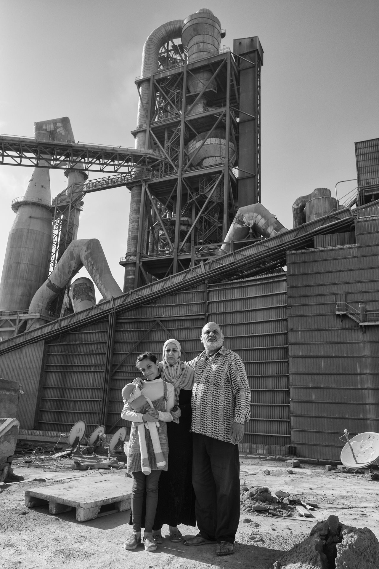 Ola, her husband Kadry, and their daughter Shahd in front of the Titan cement factory in Moon Valley, Alexandria, Egypt. They say that it feels like a monster from any angle in the area.