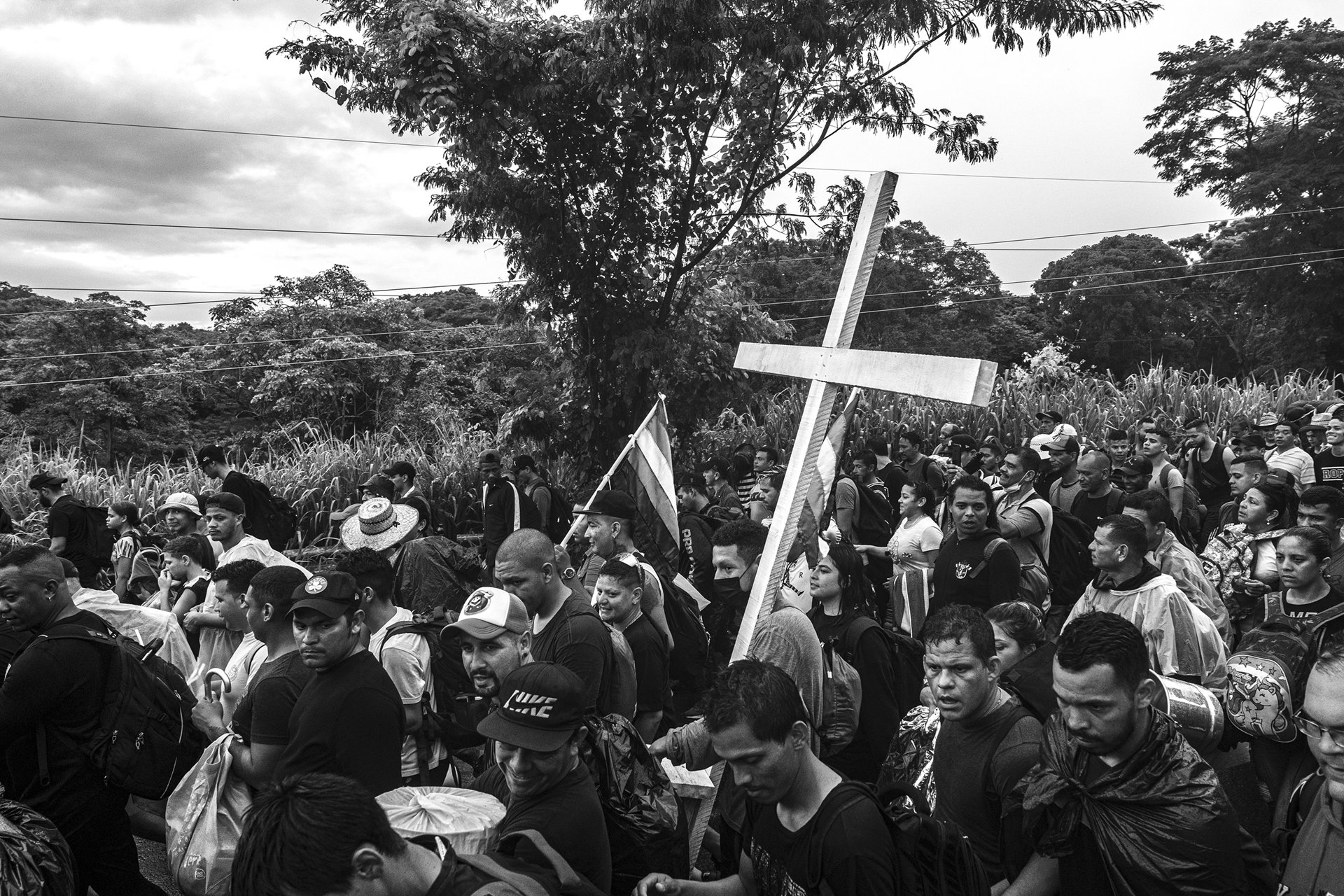A migrant carries a cross alongside a caravan composed primarily of Venezuelans in Tapachula, Mexico. Tapachula, near the border with Guatemala, serves as a compulsory stop for migrants and asylum seekers because one of the offices of the Mexican Commission for Aid to Refugees (COMAR) is located in the city. Local NGOs accuse COMAR of corruption: selling humanitarian visas to those who can afford them and deliberately delaying visas to others to curb the influx of migrants toward the US-Mexico border.