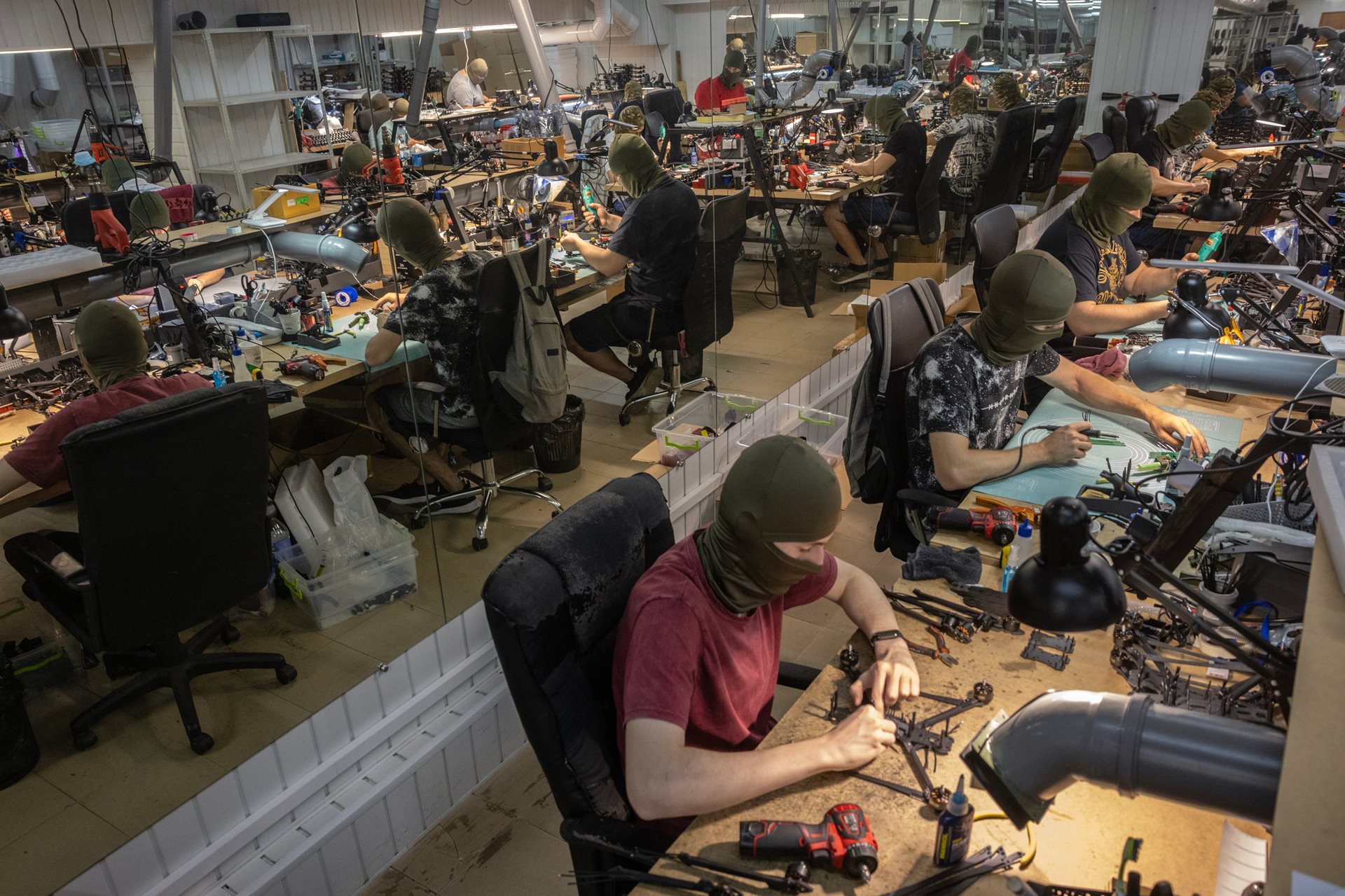 Ukrainian civilians, their identities concealed behind masks, assemble FPV drones in a basement factory in Central Ukraine. Both Ukraine and Russia now manufacture millions of battlefield drones a year.