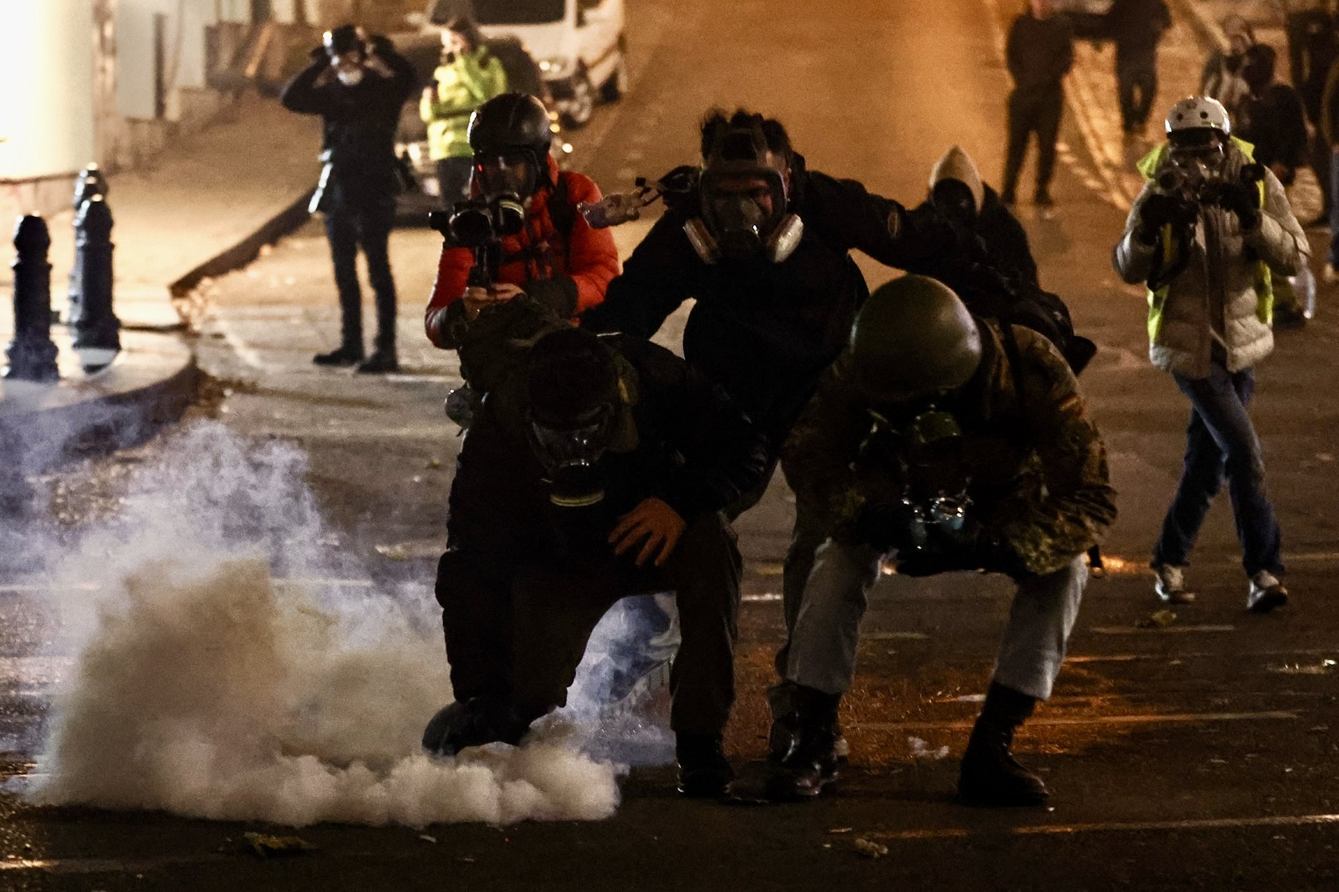 Demonstrators try to pick up a tear-gas canister to throw it away from a protest in Tbilisi, Georgia. They also used buckets or bottles of water to neutralize tear gas.