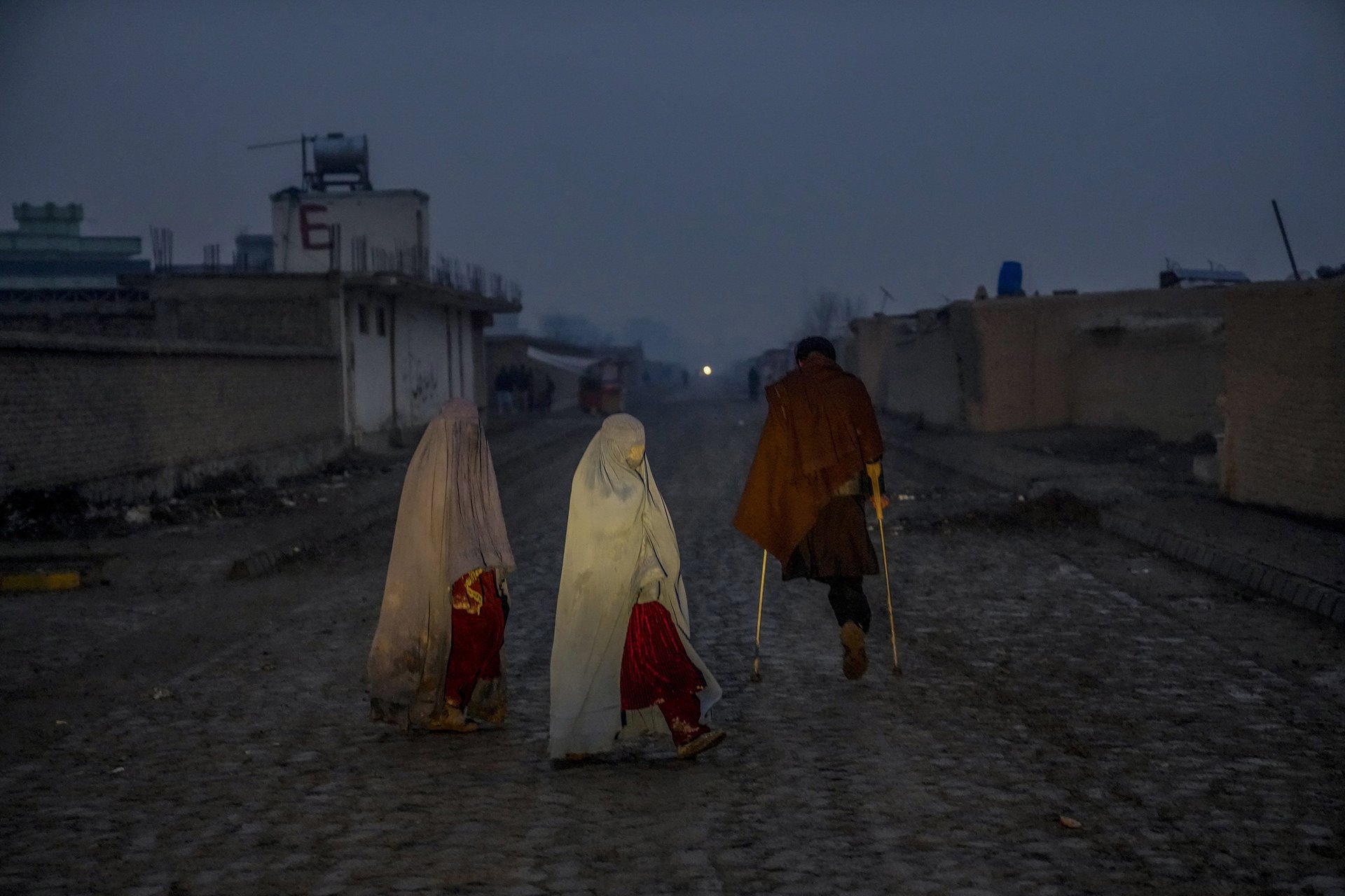 An Afghan man, who lost a leg when a suicide bomber attacked Kabul Airport in 2021, walks through a camp for internally displaced people on the outskirts of Kabul, Afghanistan.&nbsp;