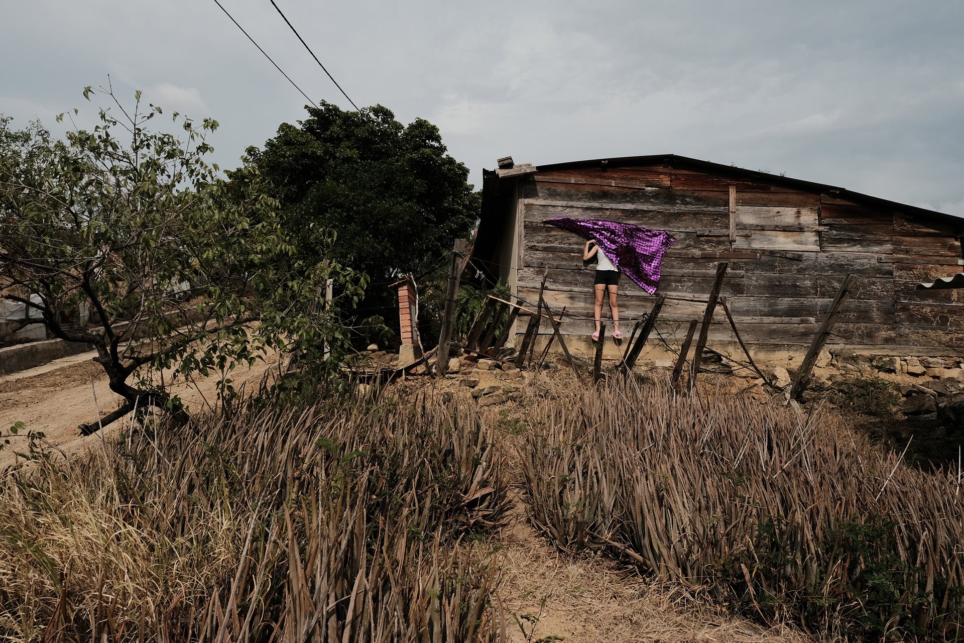 Gabriela (12) hides behind a cloth at her grandmother&rsquo;s house in Los Patios, Norte de Santander, Colombia. The house was built by her grandfather and uncle, who died due to health complications in 2016 and 2023 respectively.&nbsp;