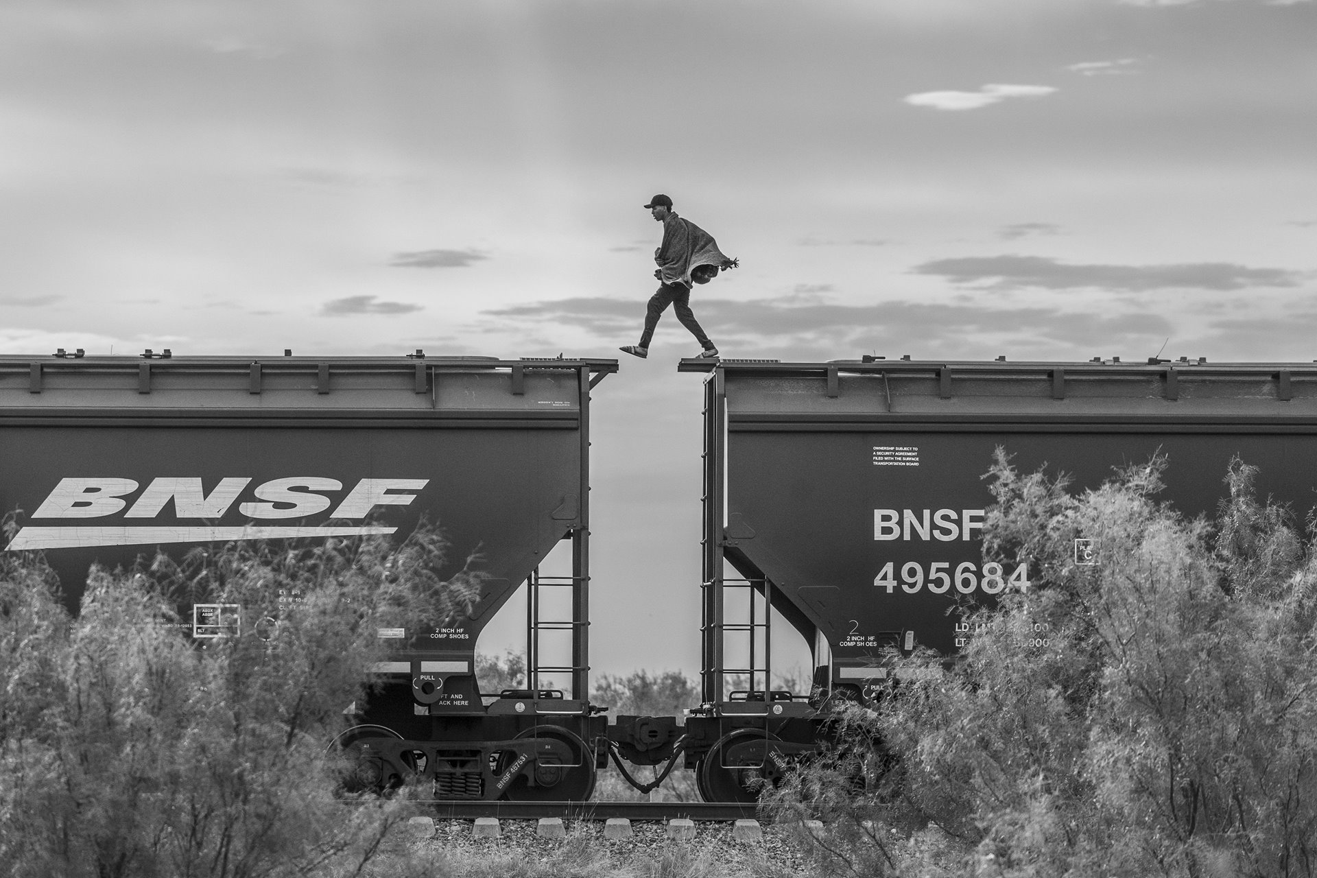 A migrant walks atop a freight train known as &ldquo;The Beast&rdquo; in Piedras Negras, Mexico. Migrants and asylum seekers lacking the financial resources to pay a smuggler often resort to using cargo trains to reach the United States border. This mode of transportation is very dangerous; over the years, hundreds have fallen onto the tracks and have been killed or mutilated. Thousands more have fallen victim to extortion, rape, kidnapping, or robbery orchestrated by drug cartels or corrupt authorities in various stops along the train&rsquo;s northward route.