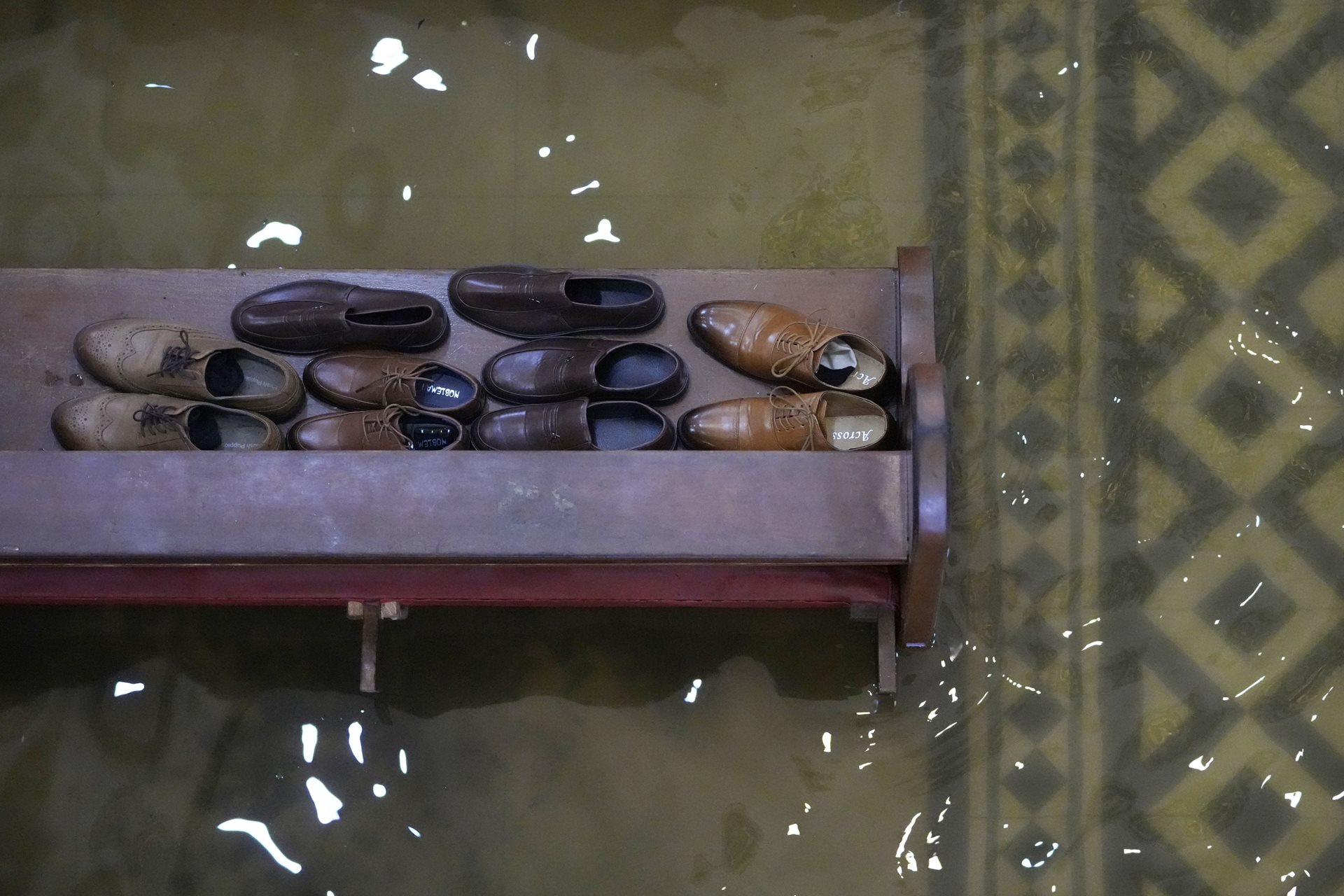 Guests leave their shoes on a church pew to keep them above the rising tide. The combined effects of the 2025 monsoon and typhoons affected over 10 million individuals and damaged more than 100,000 homes across the country. Malolos, Bulacan province, Philippines.