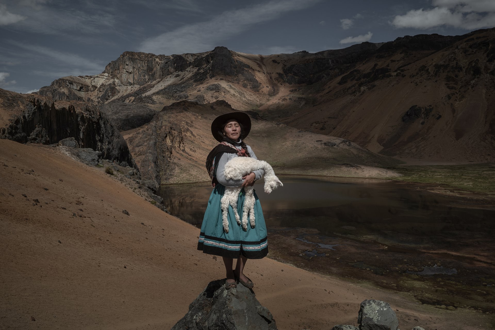 <p>Alina Surquislla Gomez, a third-generation <em>alpaquera </em>(alpaca-farmer), cradles a baby alpaca on the way to her family&rsquo;s summer pastures, in Oropesa, Peru. The climate crisis is forcing herders, many of whom are women, to search for new pastures, often in difficult terrain.</p>

