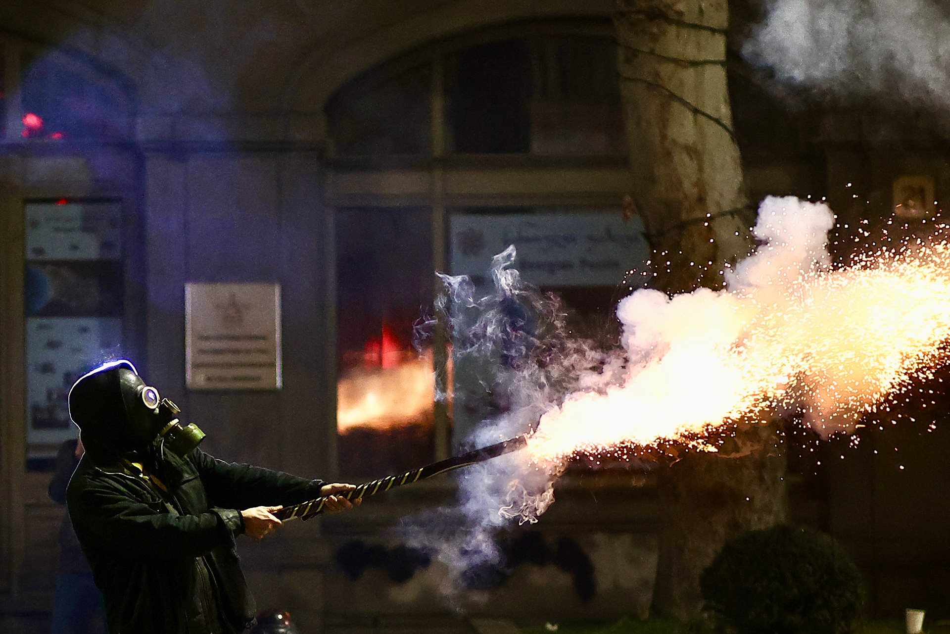 A man shoots off fireworks in response to tear gas fired by riot police, during a rally outside the Georgian parliament building on Rustaveli Avenue, in Tbilisi.