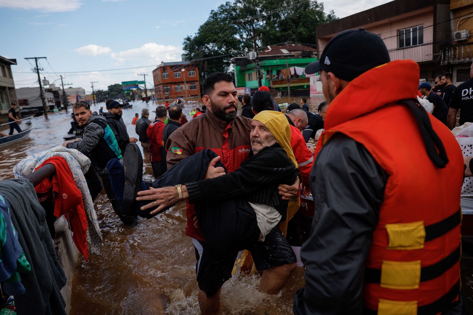 A man is carried from a boat after being rescued from floods, in Canoas, Rio Grande do Sul, Brazil. Rescue efforts prioritized the elderly, with teams navigating submerged neighborhoods to evacuate vulnerable residents.
