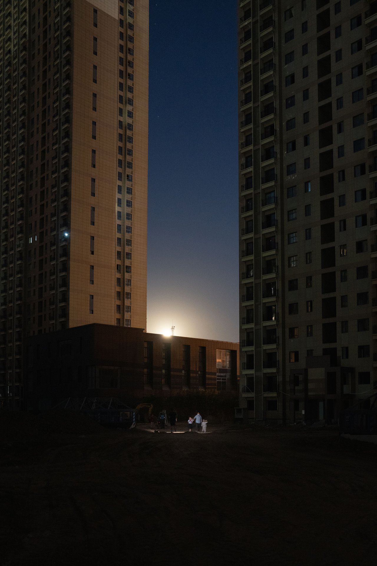 Two families greet each other by flashlight at moonrise in the Yihefang apartment complex in Xi&rsquo;an, China. Without electricity, residents make do with flashlights, solar powered lights, and an elevated sense of unity and community spirit.
