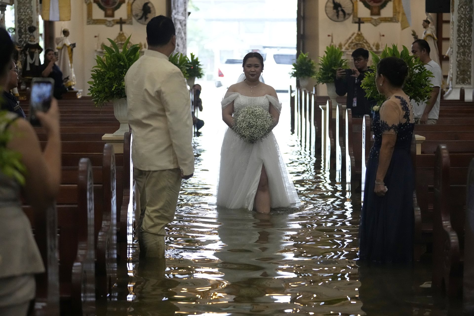 Bride Jamaica Aguilar walks down the flooded aisle of the Barasoain Church in Malolos, Bulacan province, Philippines. The night before the ceremony, the bride remained uncertain about whether to proceed, as wedding planners warned that Typhoon Wipha was intensifying the monsoon rains.