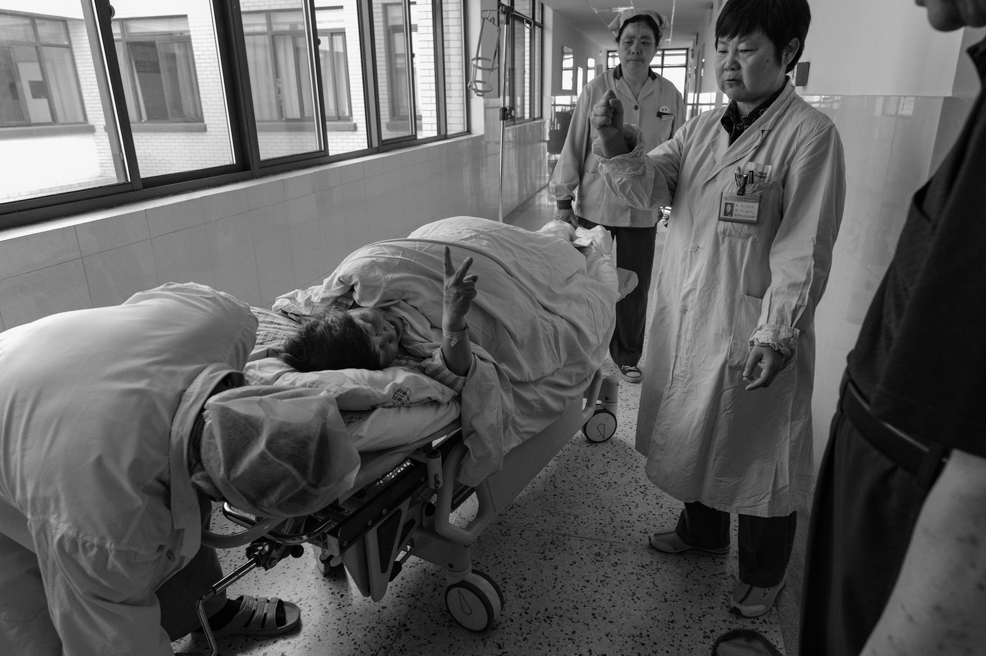 Sheng Hailin waits in a hospital corridor before entering the delivery room as her doctor offers her encouragement. A former doctor, she was acutely aware of the medical risks involved in a geriatric pregnancy but chose to proceed. Hefei, Anhui Province, China.