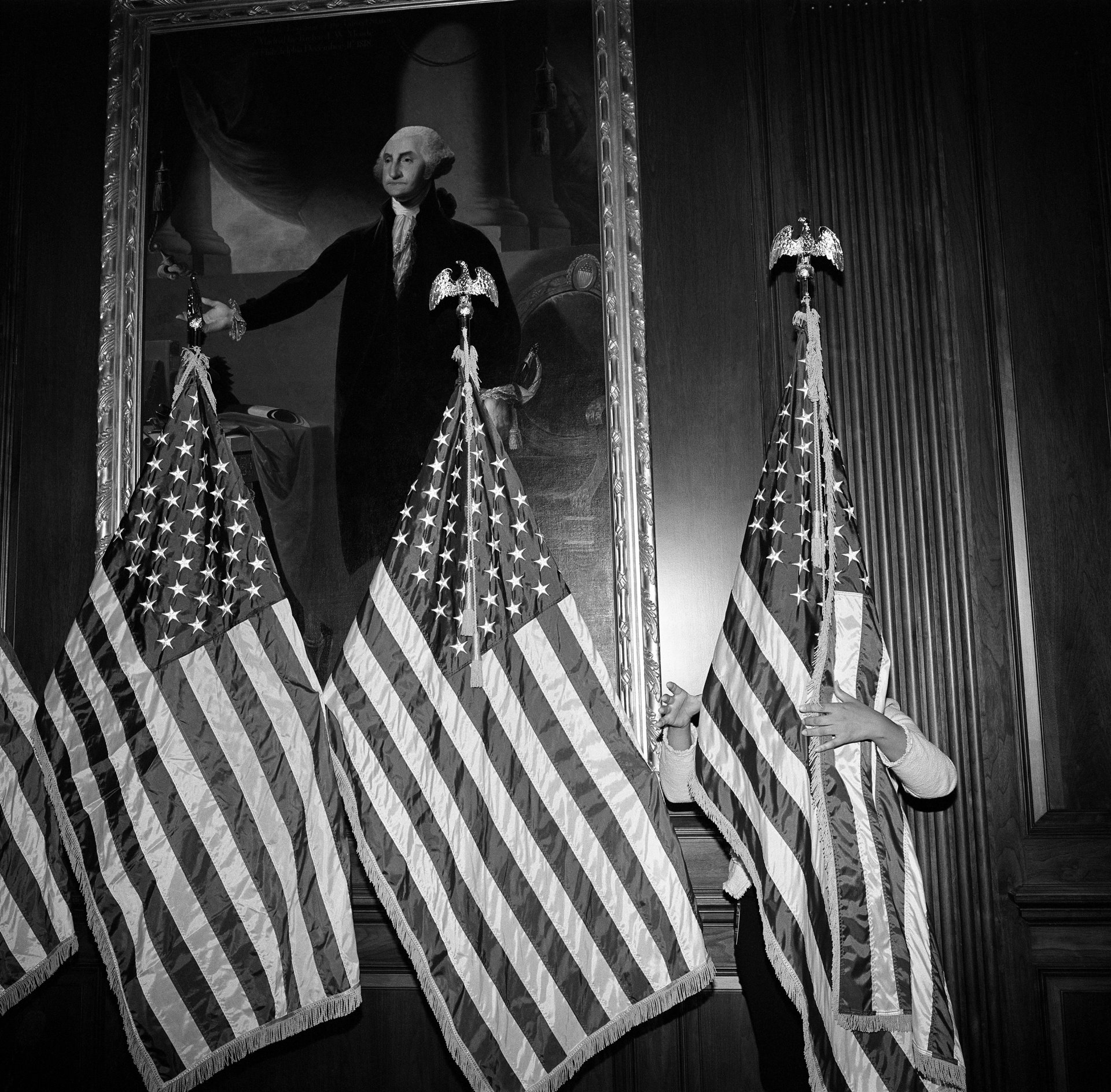 An aide to Speaker of the House of Representatives Nancy Pelosi adjusts a row of flags in front of a painting of George Washington, at the US Capitol, while preparing for Democratic leaders to speak after the vote to impeach President Donald Trump, on 18 December 2019 &ndash; the first of two occasions on which Trump was impeached. The US House of Representatives impeached the president for abusing his power by trying to coerce Ukraine into investigating Joe Biden, then a leading contender for the Democratic nomination to run against him, by allegedly threatening to withhold military aid. A second charge was laid &nbsp;against the president for obstructing Congress by ordering his administration to not cooperate with the investigation. Trump was later acquitted on both charges by the US Senate.