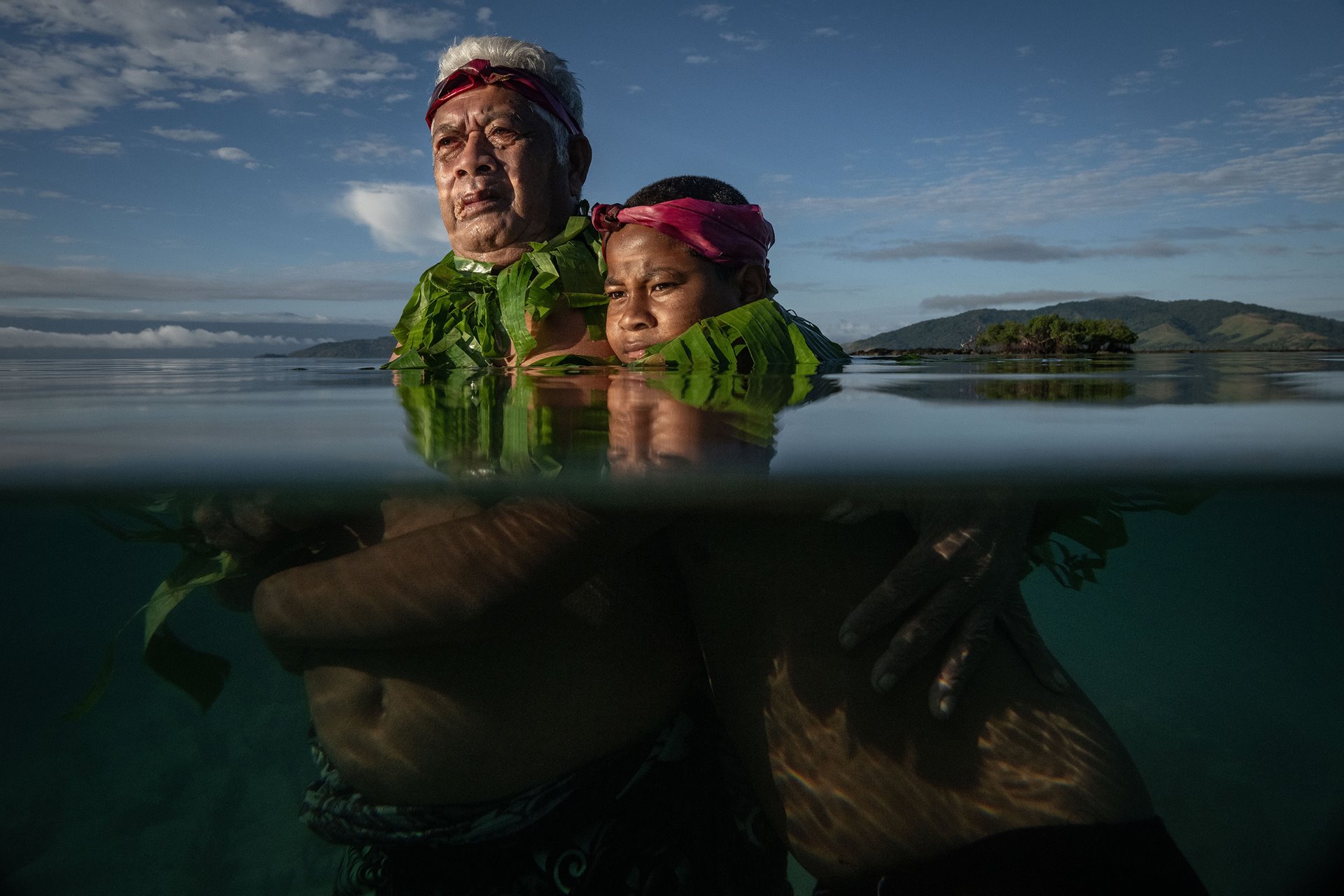 Lotomau Fiafia (72), a community elder, stands with his grandson John at the point where he remembers the shoreline used to be when he was a boy. Salia Bay, Kioa Island, Fiji.
