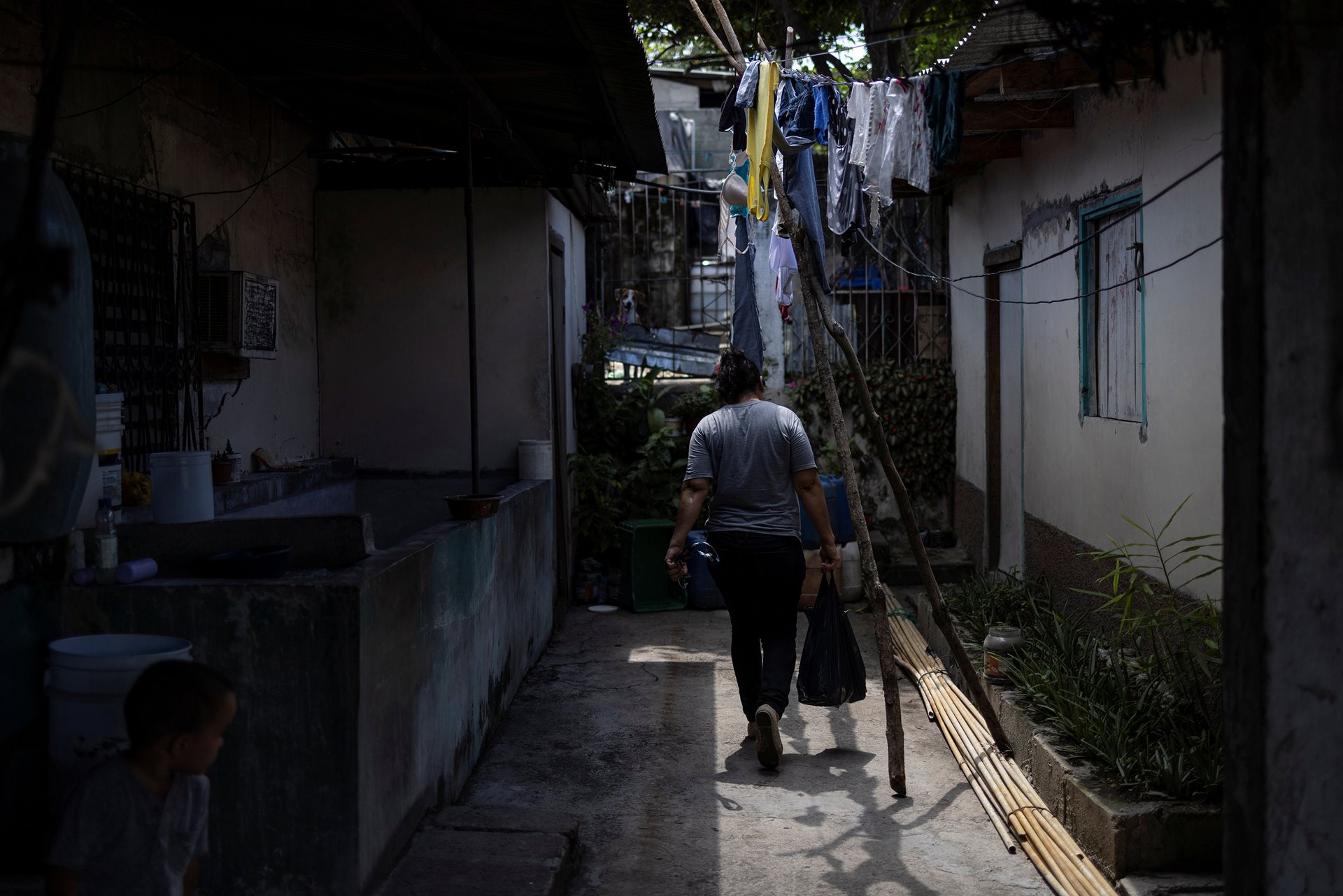 <p>Maria Hernandez walks home from shopping in San Pedro Sula, Honduras, while awaiting a decision on her immigration case, in order to travel to the United States to reunite with her daughters.</p>
