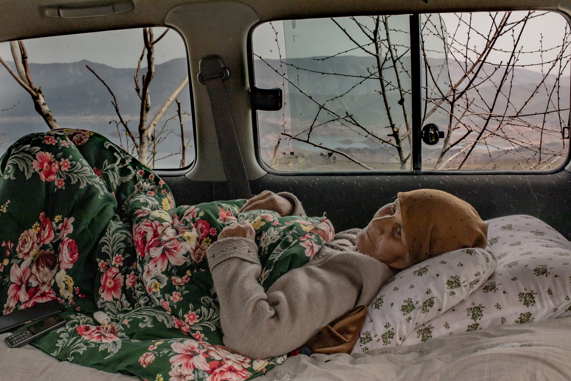 Ranobi Islomova (63), who is ill, waits to be taken to a nearby town, in a car beside the Norak Reservoir in south-eastern Tajikistan.