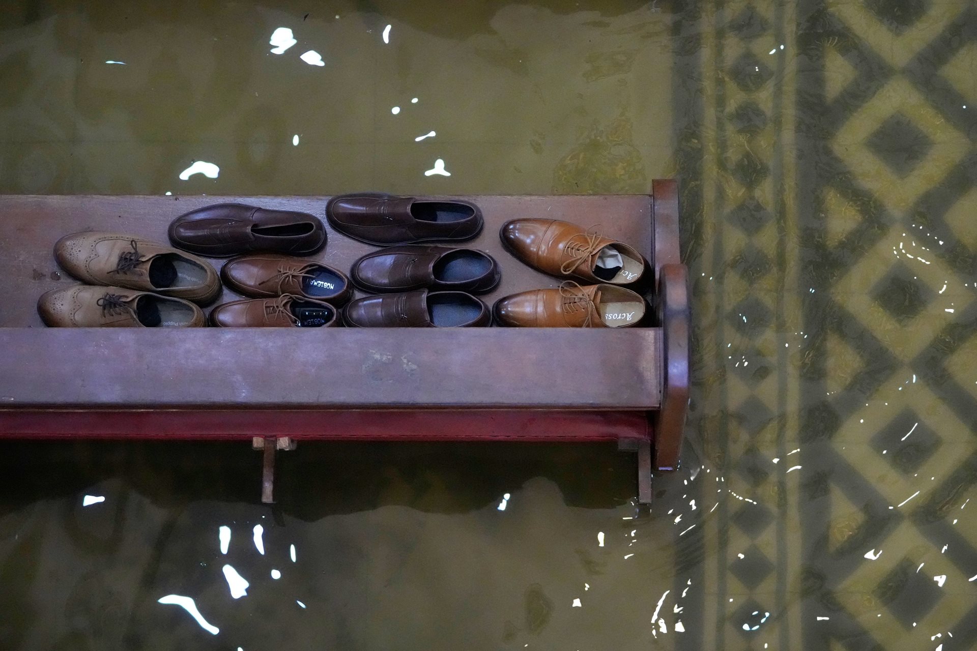 Guests leave their shoes on a church pew to keep them above the rising tide. The combined effects of the 2025 monsoon and typhoons affected over 10 million individuals and damaged more than 100,000 homes across the country. Malolos, Bulacan province, Philippines.