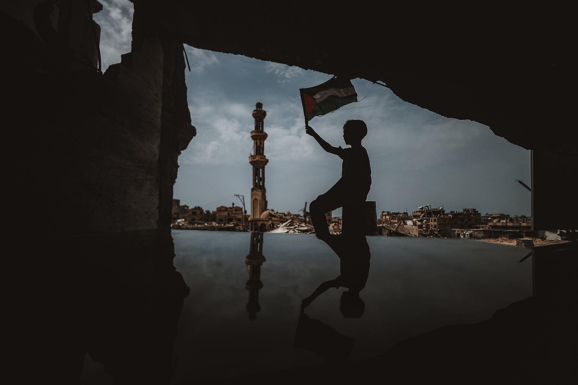 A boy waves a Palestinian flag over a city devastated by Israeli bombardment, in Khan Younis, Gaza. In April, Israeli forces withdrew from Khan Younis, which had become an epicenter of the war, and citizens began to return and recover something of everyday life. However, further Israeli incursions to the city occurred later in the year, and continued into 2025.