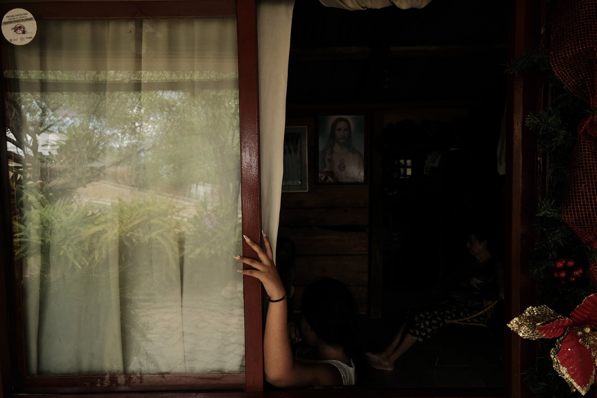 María (20), the photographer&rsquo;s cousin, watches television with her grandmother, Orfelina. The living room serves as the primary gathering space where the women of the household meet to share daily life and watch the news. Los Patios, Norte de Santander, Colombia.