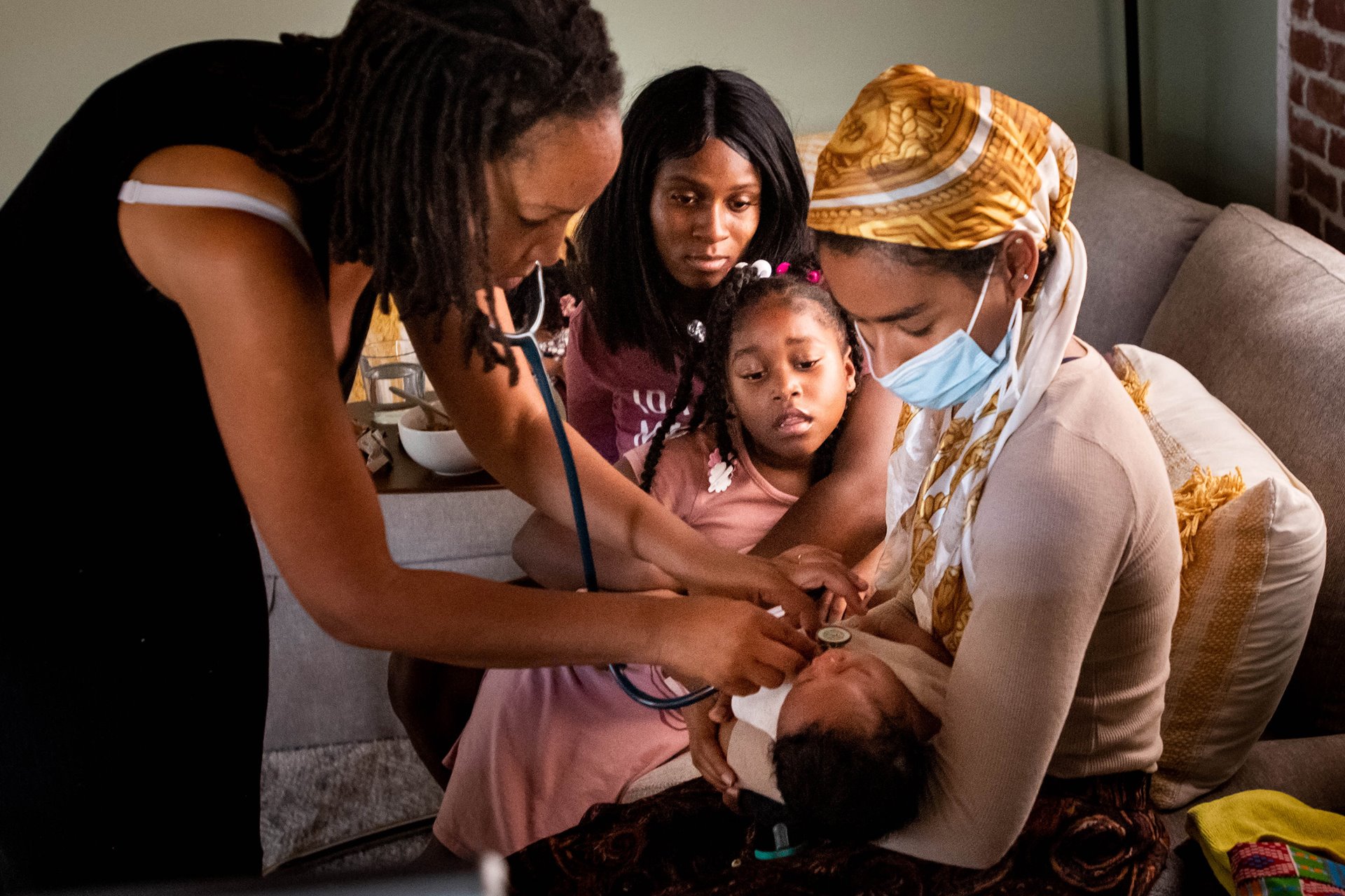 Aysha and her daughter Nyla watch midwife Allegra Hill and student midwife Maryam Karim listen to two-week-old Nikko&#39;s heart, during a postpartum visit to the Kindred Space LA birthing center, in South Los Angeles, USA.