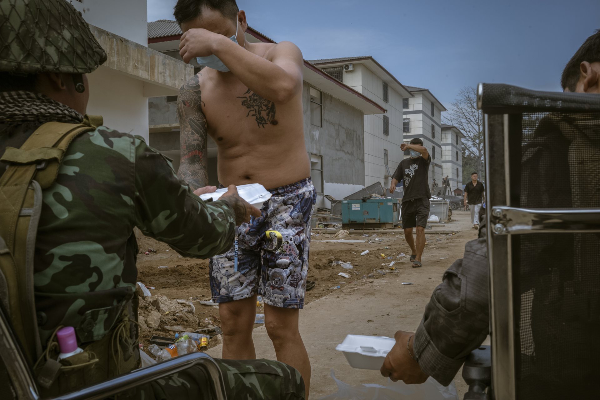 Workers cover their faces as they receive food rations from Karen National Liberation Army soldiers. The &ldquo;liberation&rdquo; of the camp turned many scam center employees into refugees who wanted to avoid being identified by international law enforcement or their former captors. Min Let Pan, Myanmar.