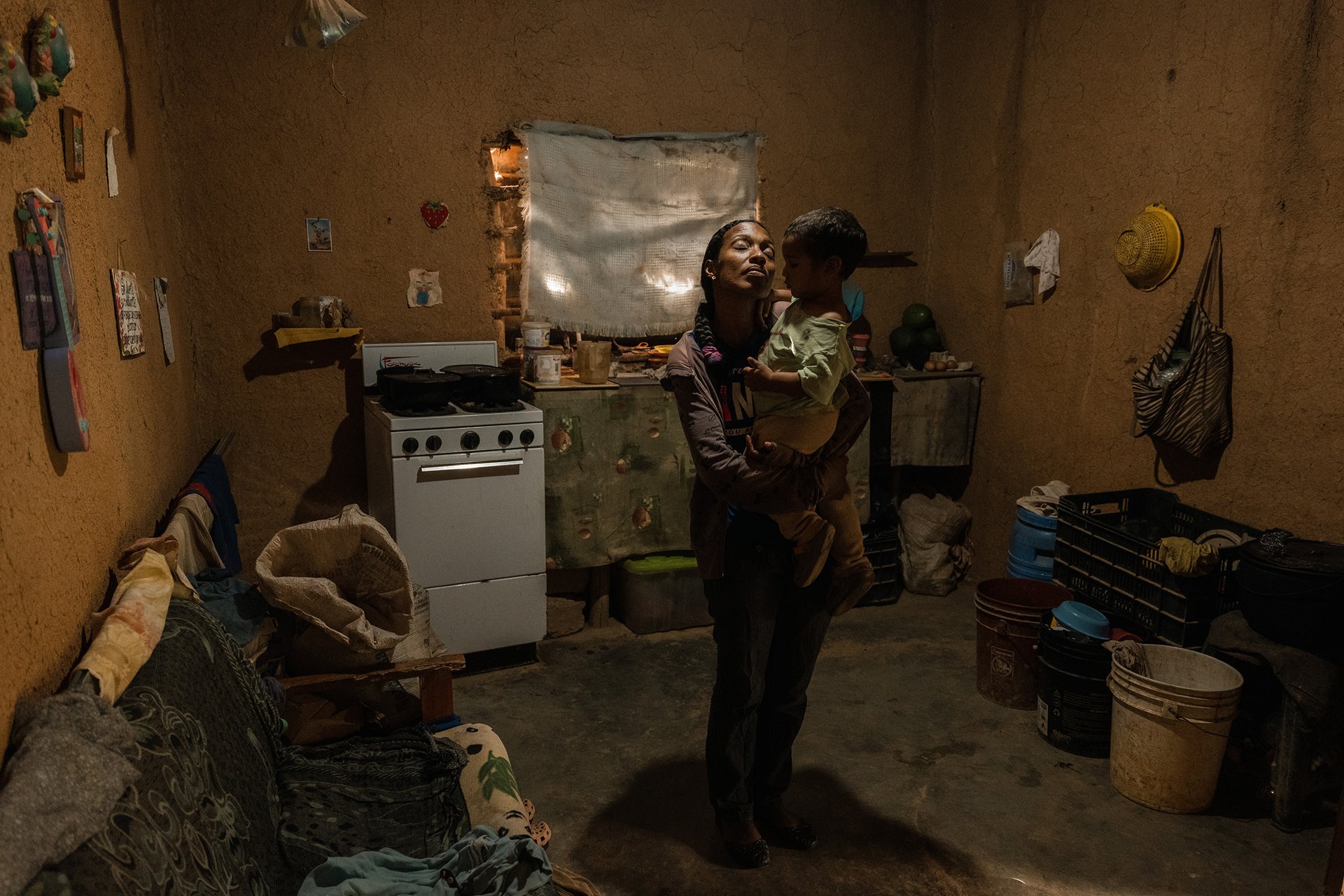 Yrelys Jimenez (38) holds her son, Yonder Lopez-Jimenez (2), under a hole carved in the roof of the family home by heavy rain, in San Diego de Los Altos, Caracas, Venezuela. Her US$6 monthly salary barely covers her basic needs, so she plants beans and avocados to barter with her neighbors.&nbsp;