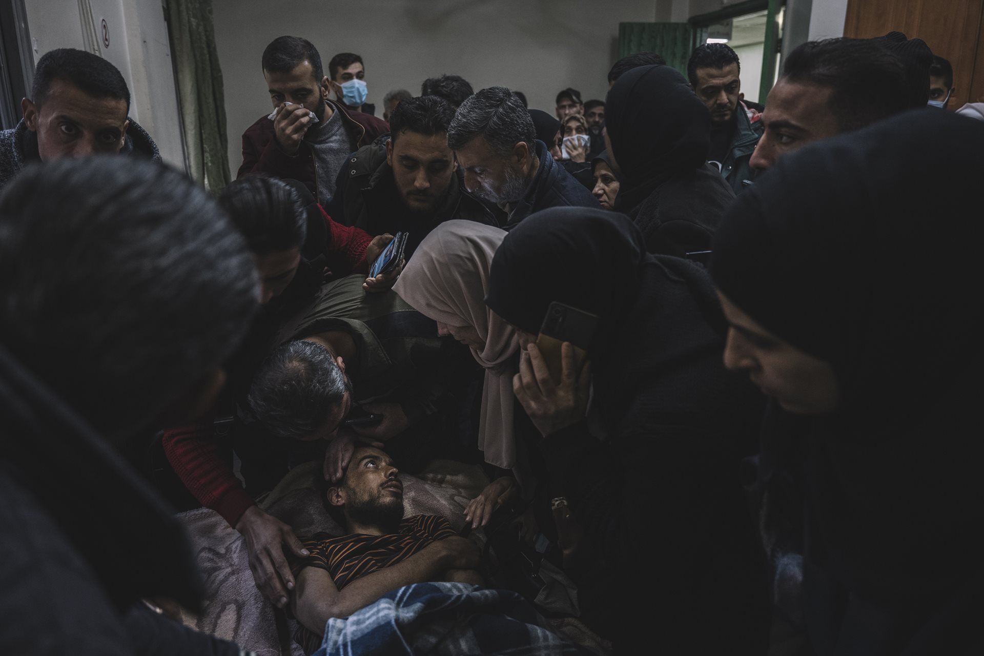 Relatives of people who have been missing for years crowd around a man transferred from Sednaya prison to the Ibn Al-Nafees Hospital, in Damascus, Syria. Desperate for news, although he can barely speak, they form a human wall around him showing photos of their relatives on their phones.&nbsp;
