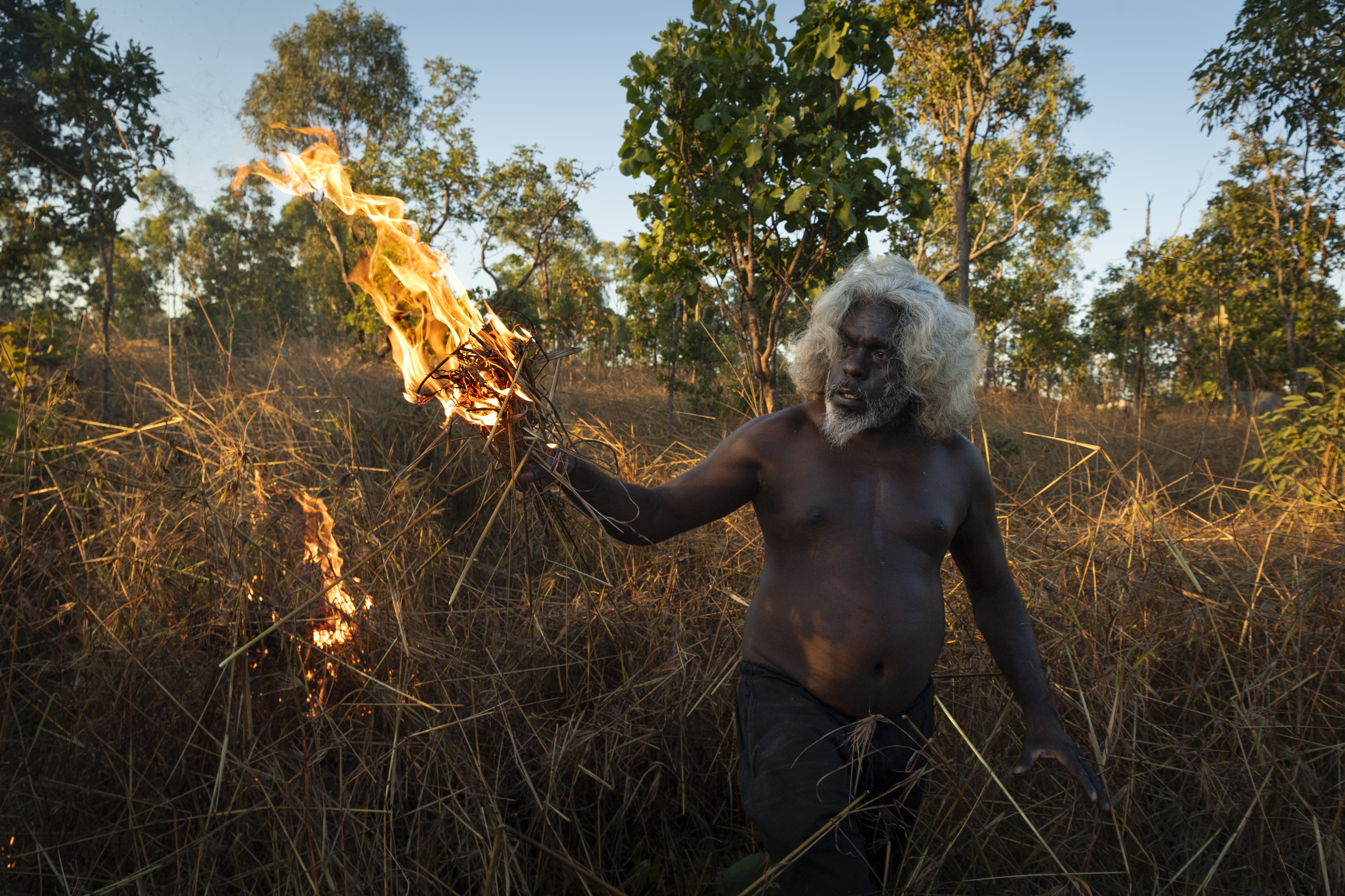 Nawarddeken elder Conrad Maralngurra burns grass to protect the Mamadawerre community from late-season wildfires, in Mamadawerre, Arnhem Land, Australia. The late-evening fire will die out naturally once the temperature drops and moisture levels rise.
