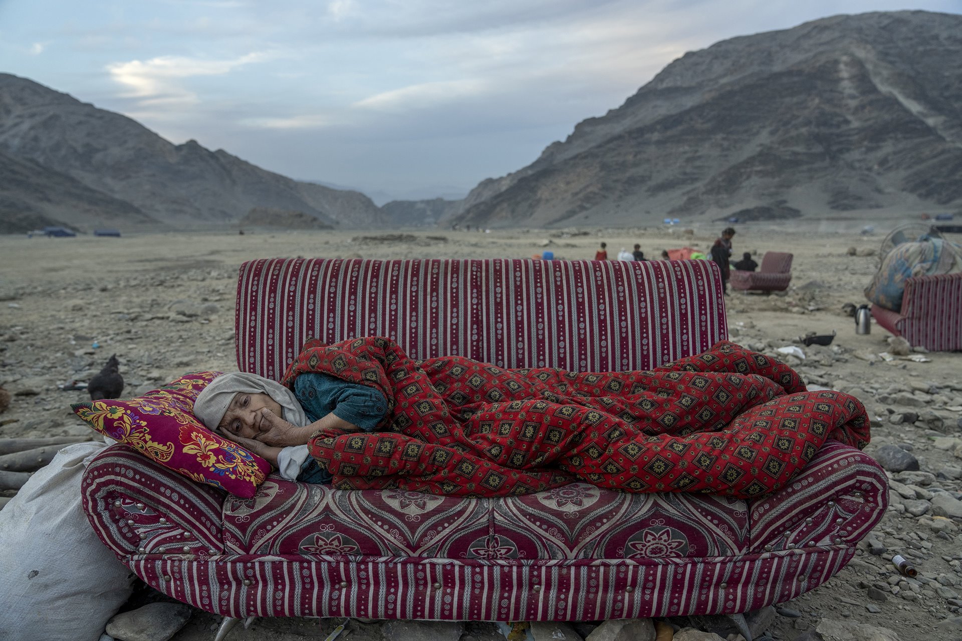An Afghan woman rests in the desert, near a camp housing people recently deported from Pakistan, in Torkham, Afghanistan, close to the Pakistan-Afghanistan border. Hundreds of thousands of refugees crossed the border in the weeks around the Pakistan government&rsquo;s 1 November deadline for the deportation of undocumented Afghans from the country.&nbsp;