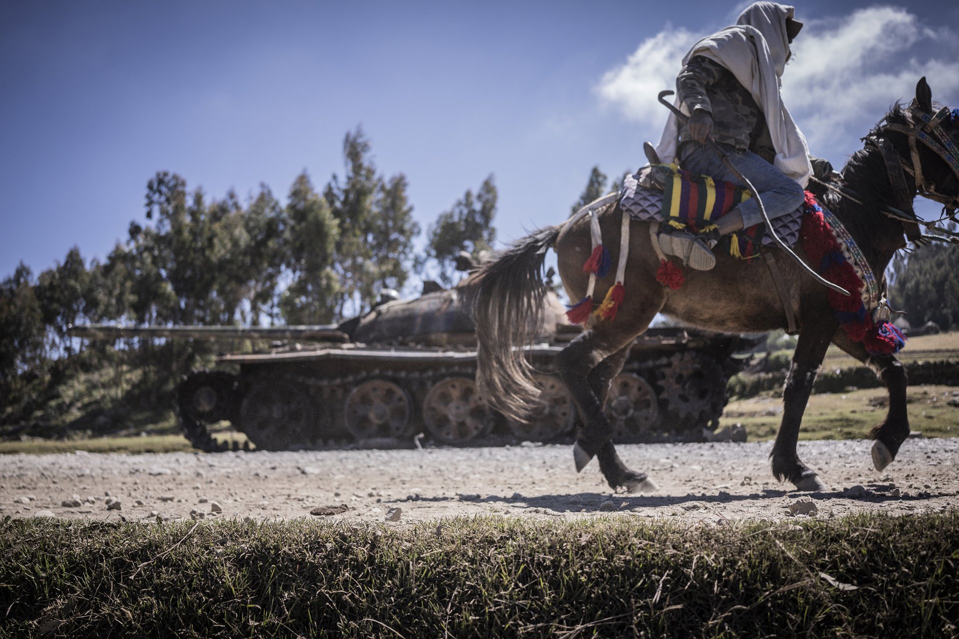 A rider passes a destroyed tank, in Mesobit, Amhara, Ethiopia.