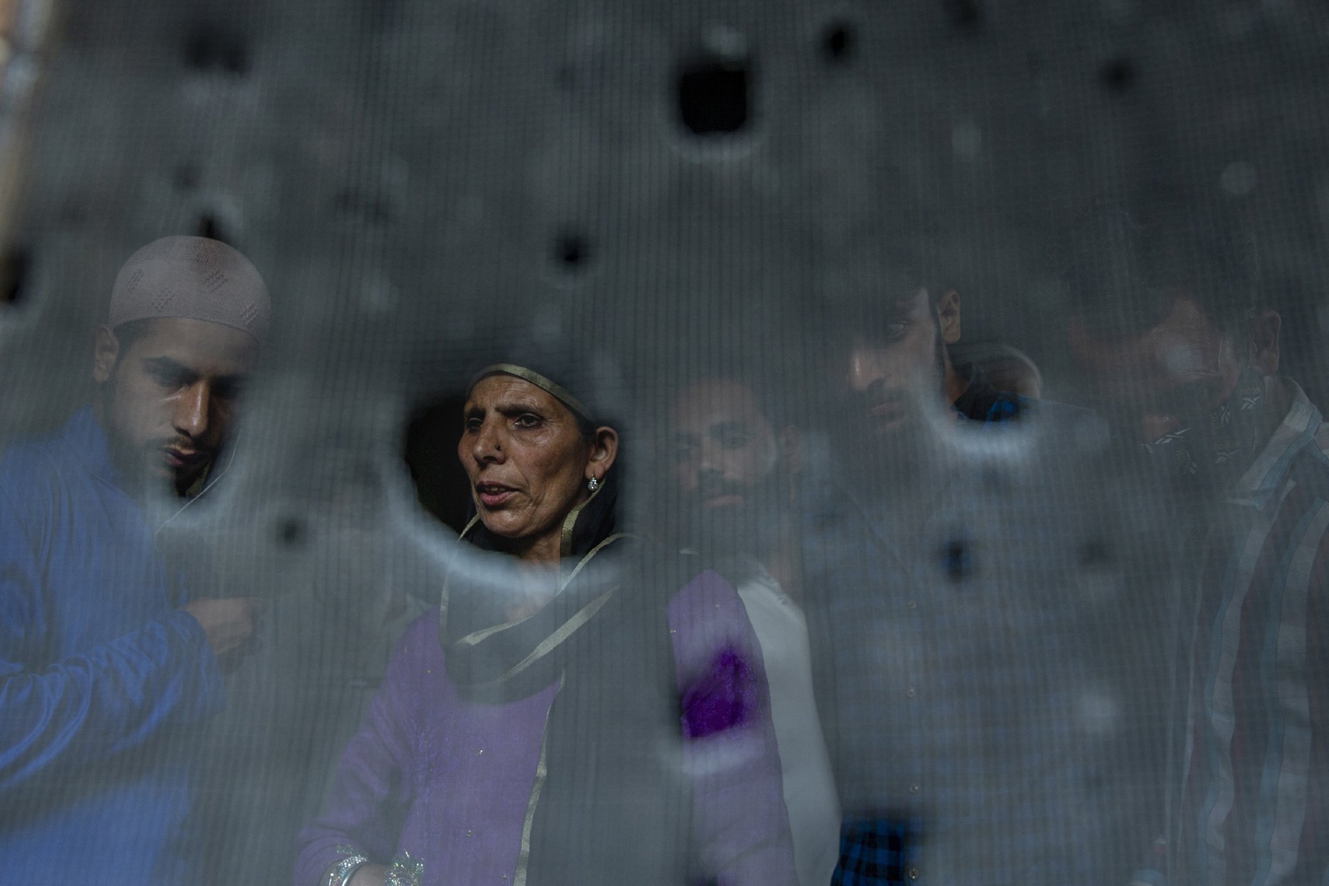 Kashmiri villagers are seen through the bullet-ridden iron mesh of a window of a home where suspected militants had taken refuge, in Pulwama, south of Srinagar, in Indian-administered Kashmir. Officials said that five suspected militants and an army soldier were killed in a shoot-out.