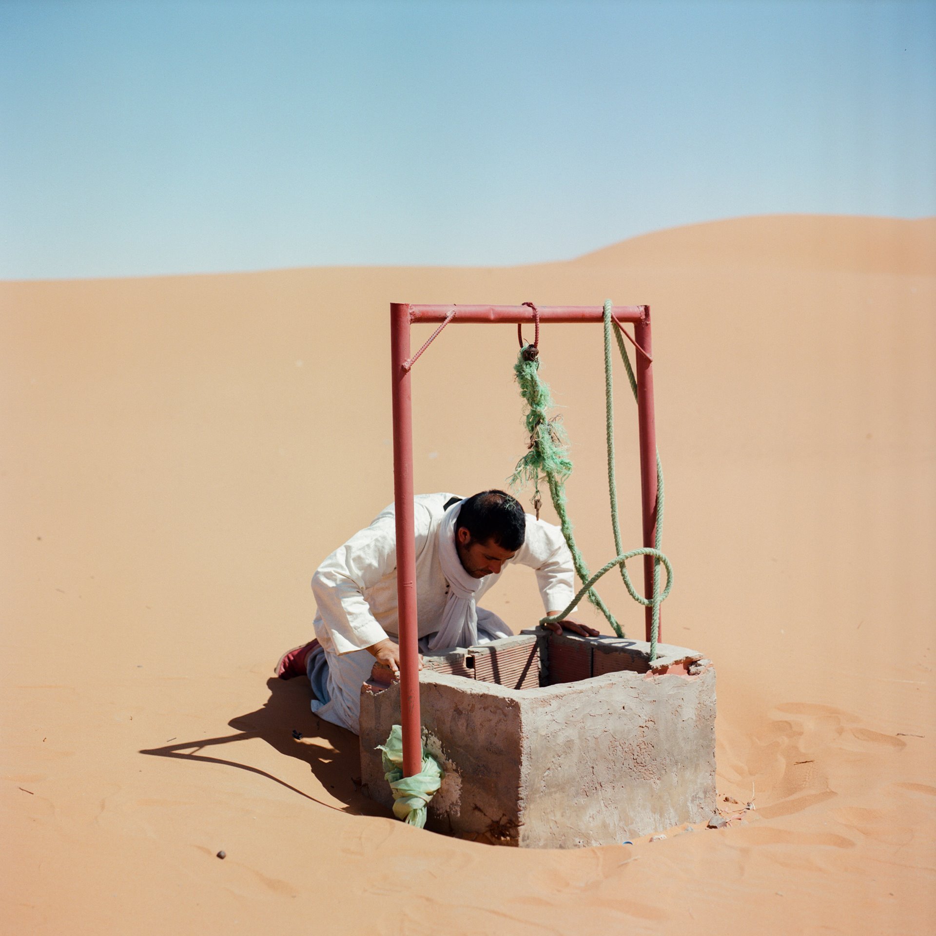 <p>A man checks the water level of a well at Merzouga Oasis, in eastern Morocco. Deep wells can deplete the water table, leaving farmers without a water supply.</p>
