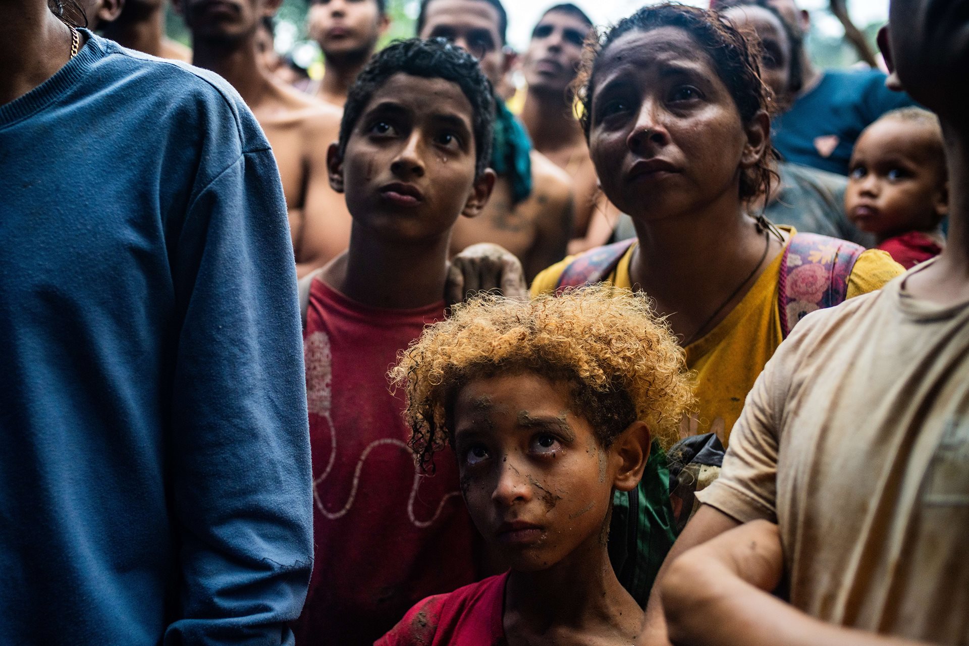 Sebastian Colmenares (8) is moved to tears as he listens to a speech by an indigenous leader in the El Abuelo community, a town that many migrants find after crossing the Darién Gap. Behind him, his older brother Juan Colmenares (10) and their mother, Enlgymar Galinde, are also weeping, overwhelmed by a mix of emotions after emerging from the jungle.