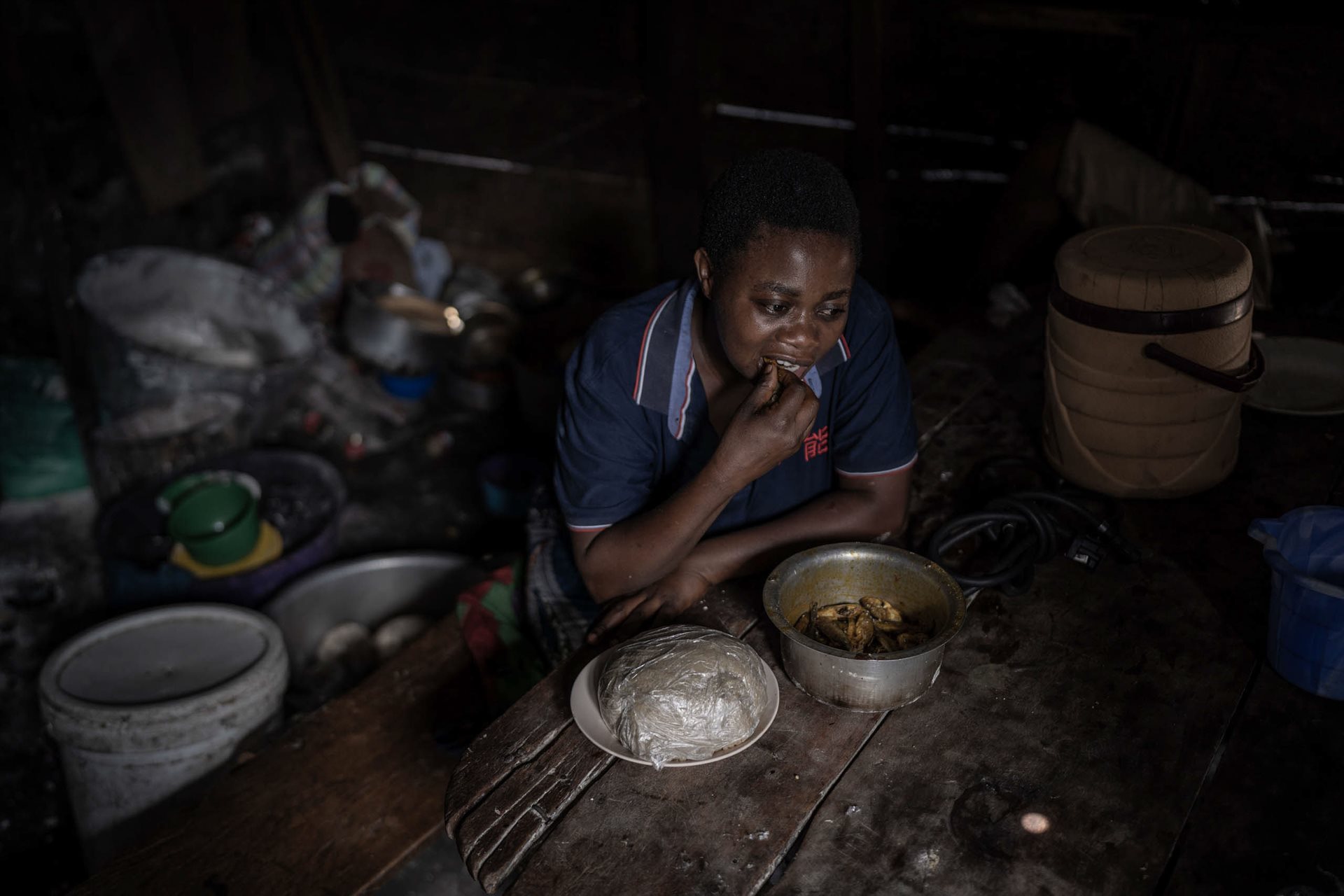 A woman eats sambaza and fufu at a restaurant in Goma, DRC.
